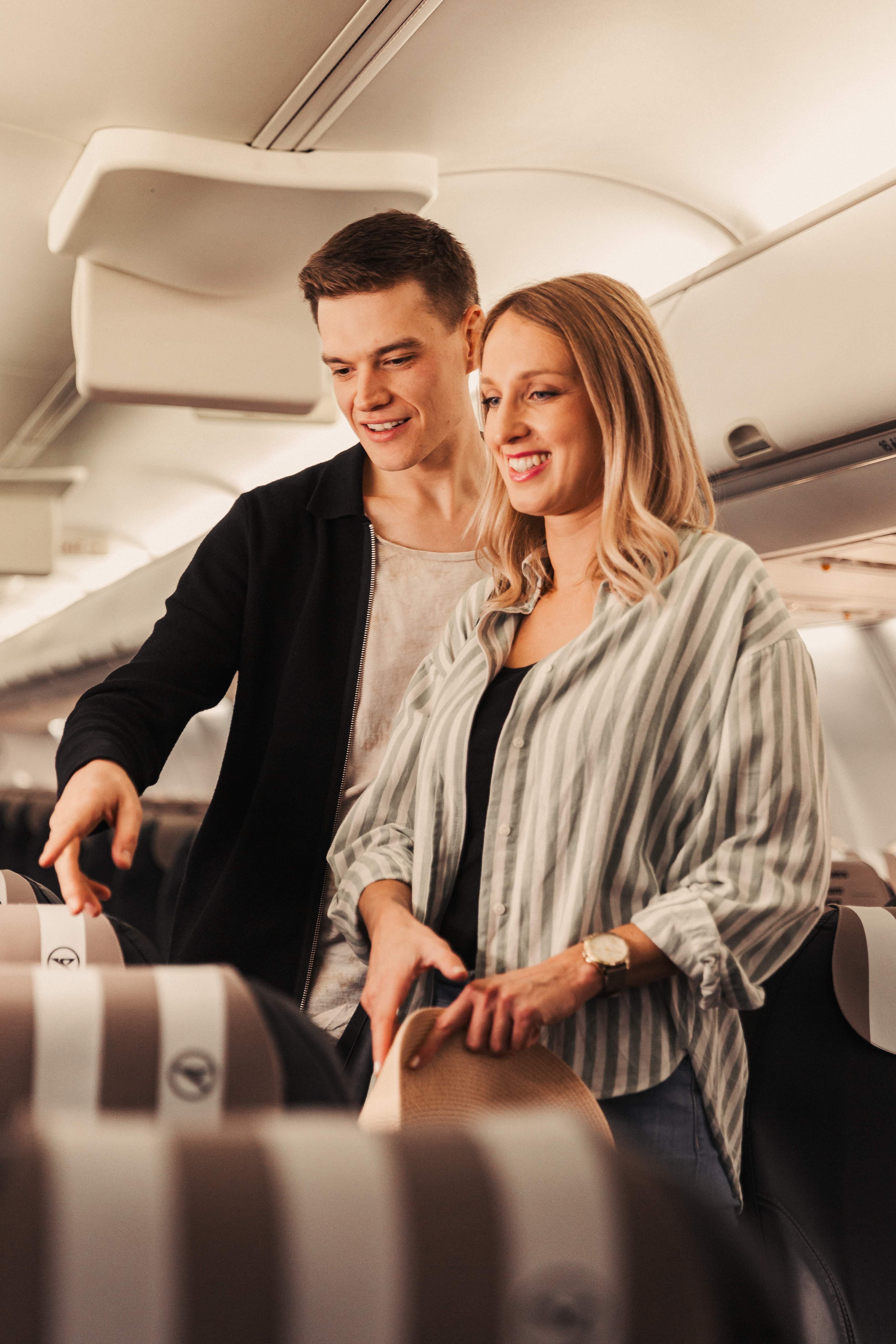 una pareja joven está de pie en un B757 en Business Class y busca asientos adecuados