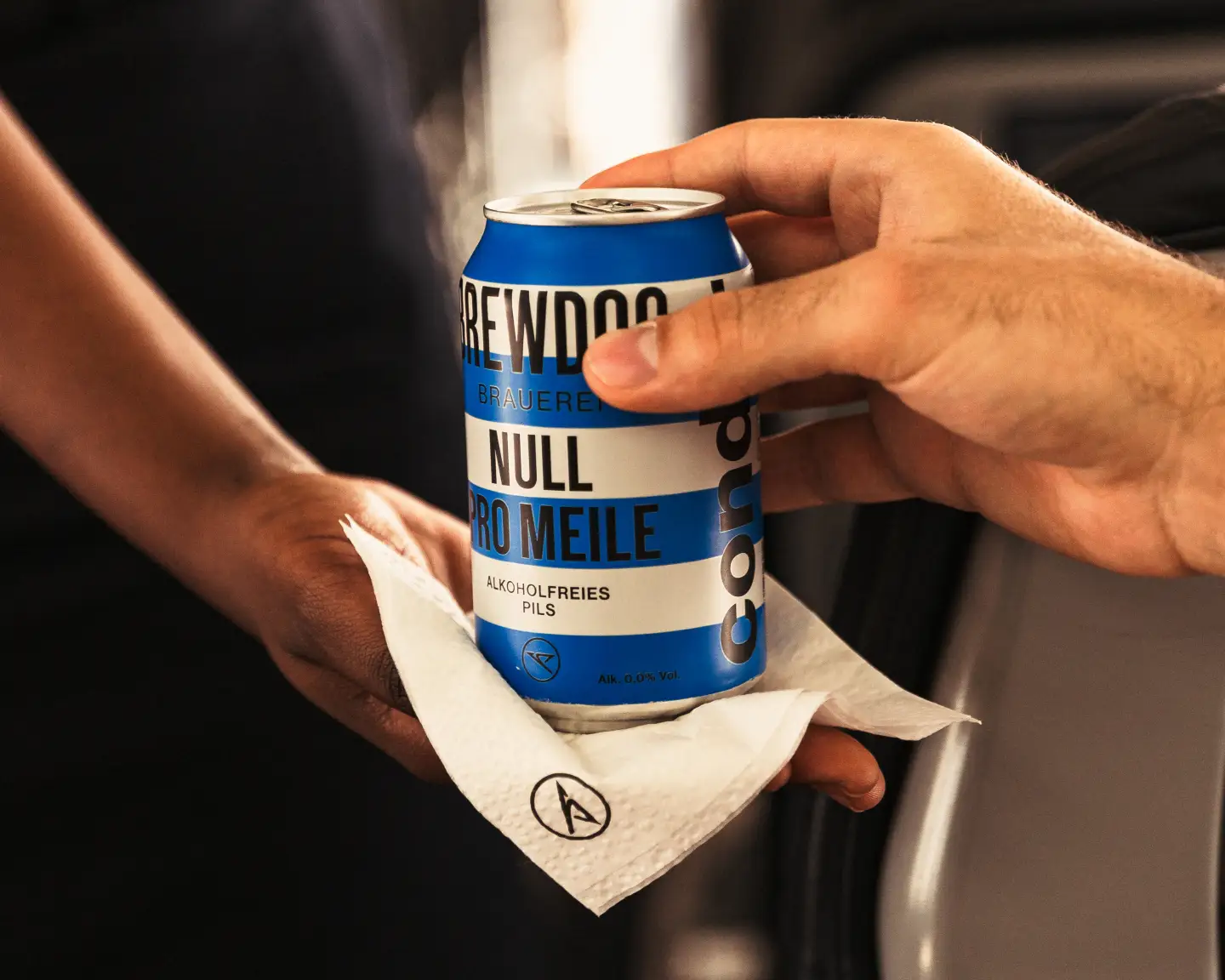 Un auxiliar de vuelo entrega a un pasajero una lata de Brewdog "Null pro Meile".