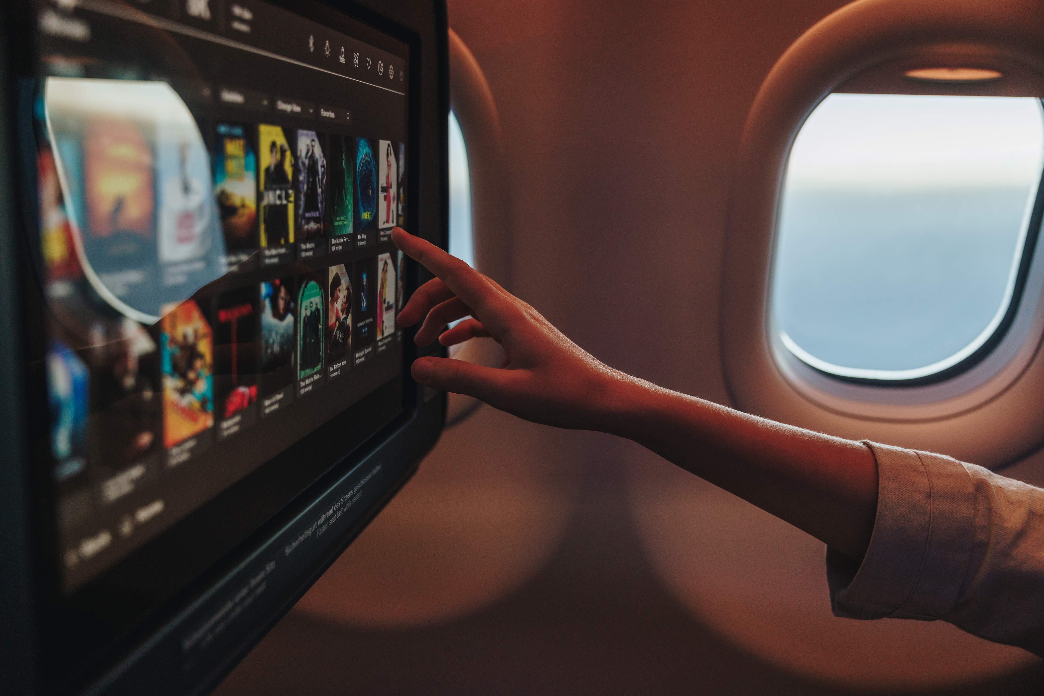 A passenger is selecting a film on his personal screen in Condor Inflight Entertainment