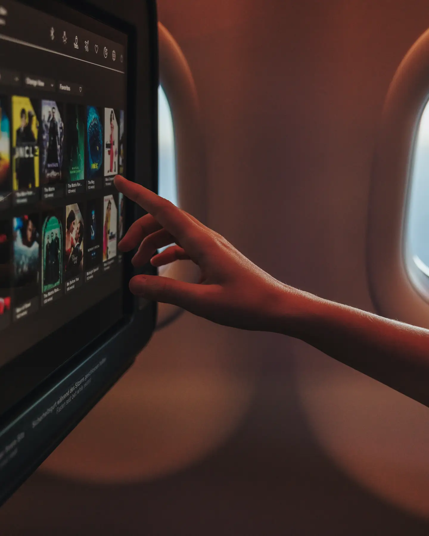 A passenger is selecting a film on his personal screen in Condor Inflight Entertainment