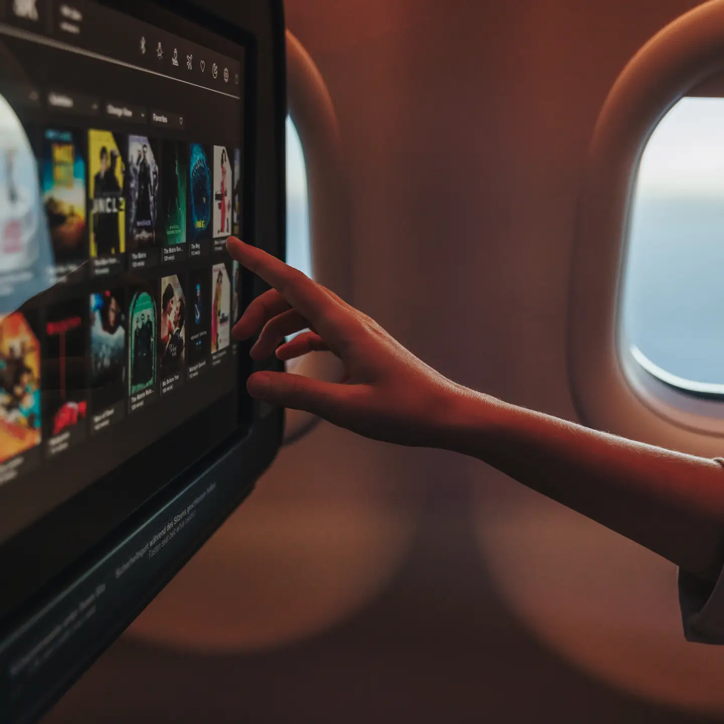 A passenger is selecting a film on his personal screen in Condor Inflight Entertainment