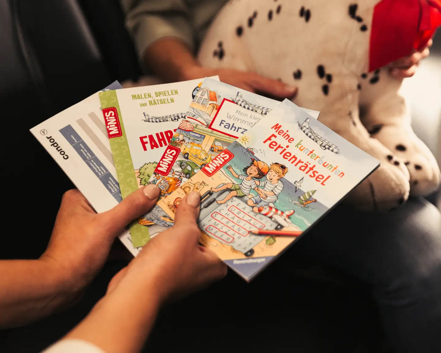 Persona que sostiene libros de actividades infantiles en un avión de Condor.
