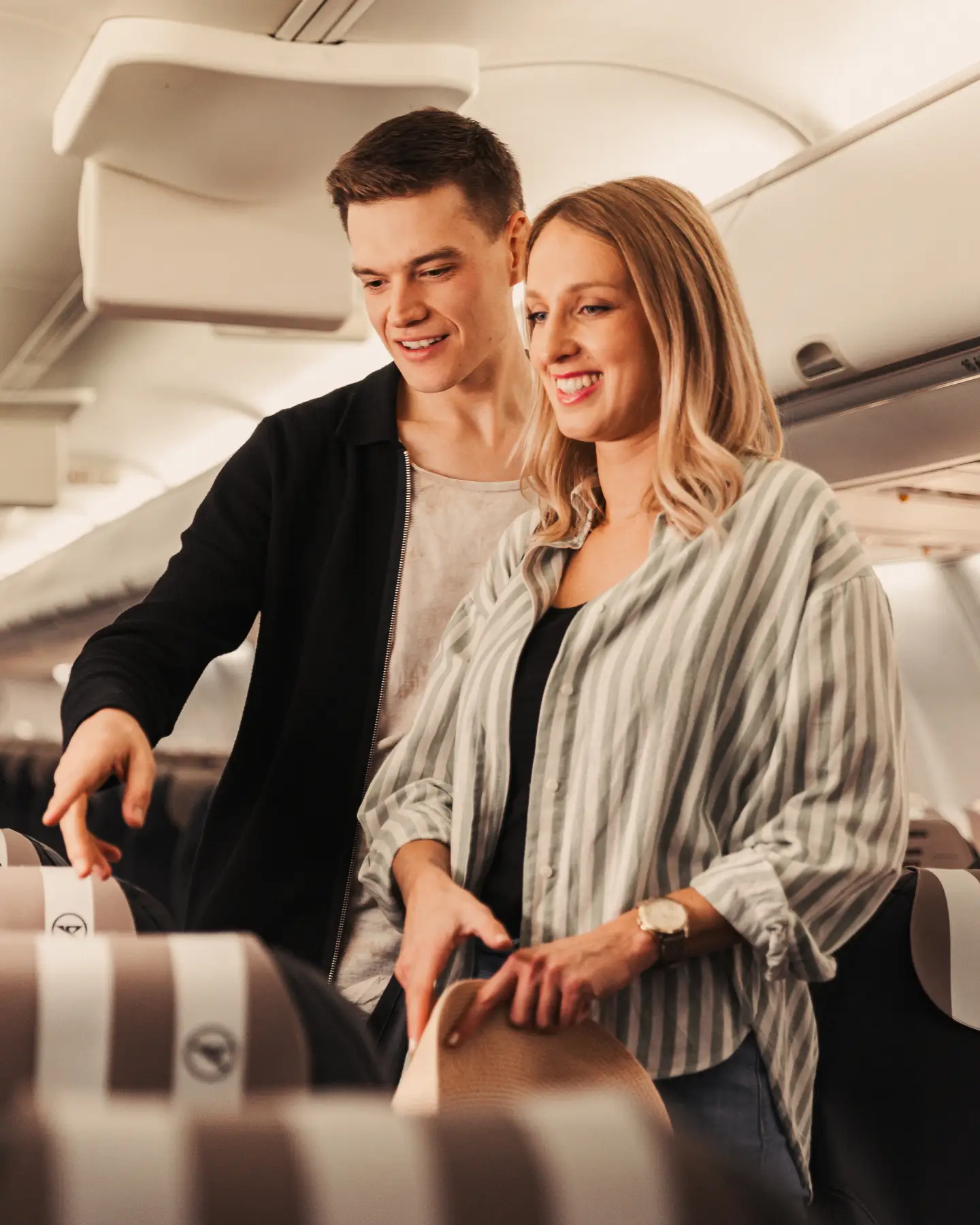 Een jong stel staat in een B757 in Business Class en is op zoek naar geschikte stoelen