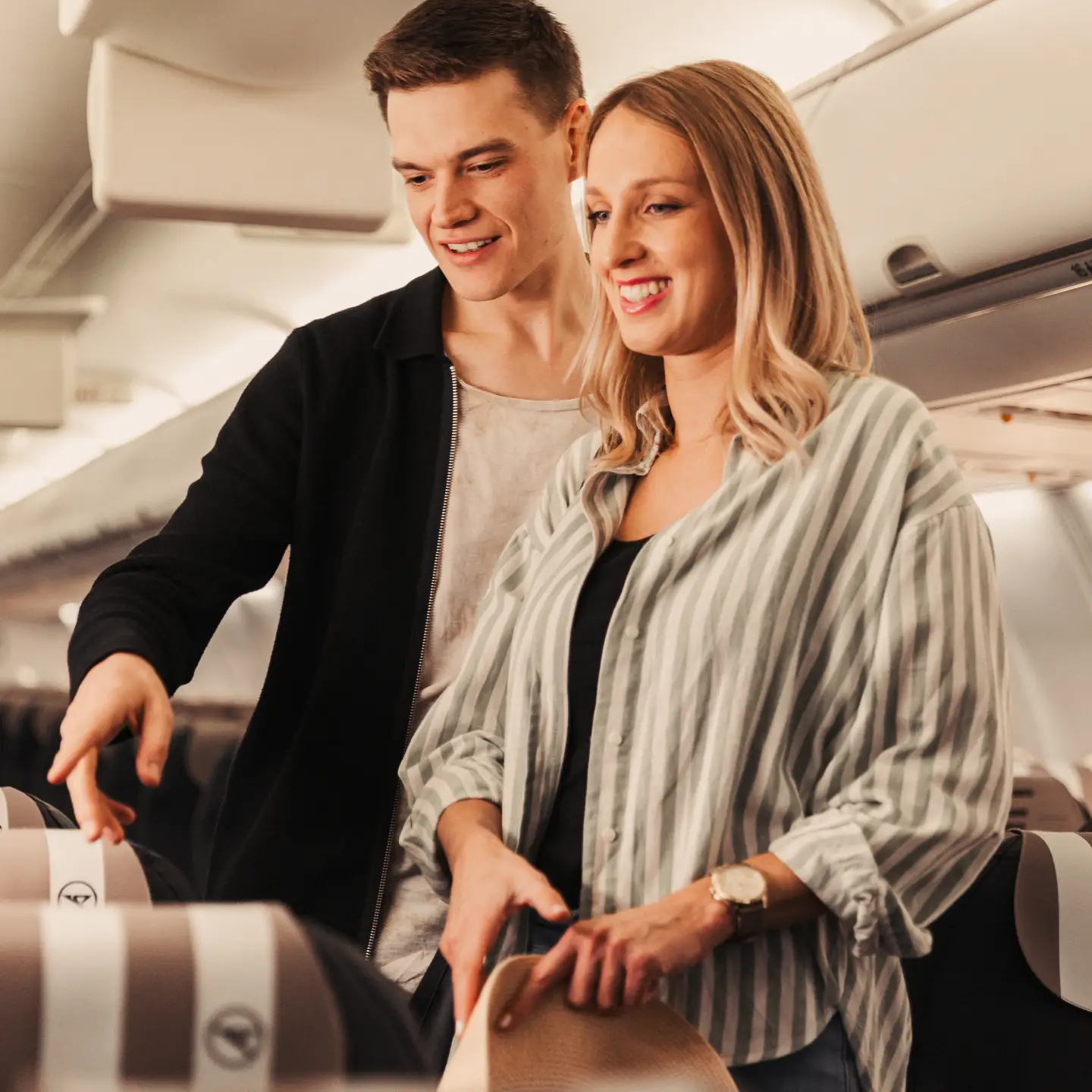 Een jong stel staat in een B757 in Business Class en is op zoek naar geschikte stoelen