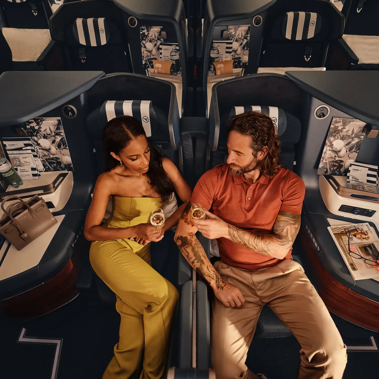 En el Airbus A330neo, una pareja está sentada en asientos Prime Seat de Business Class, bebiendo champán.