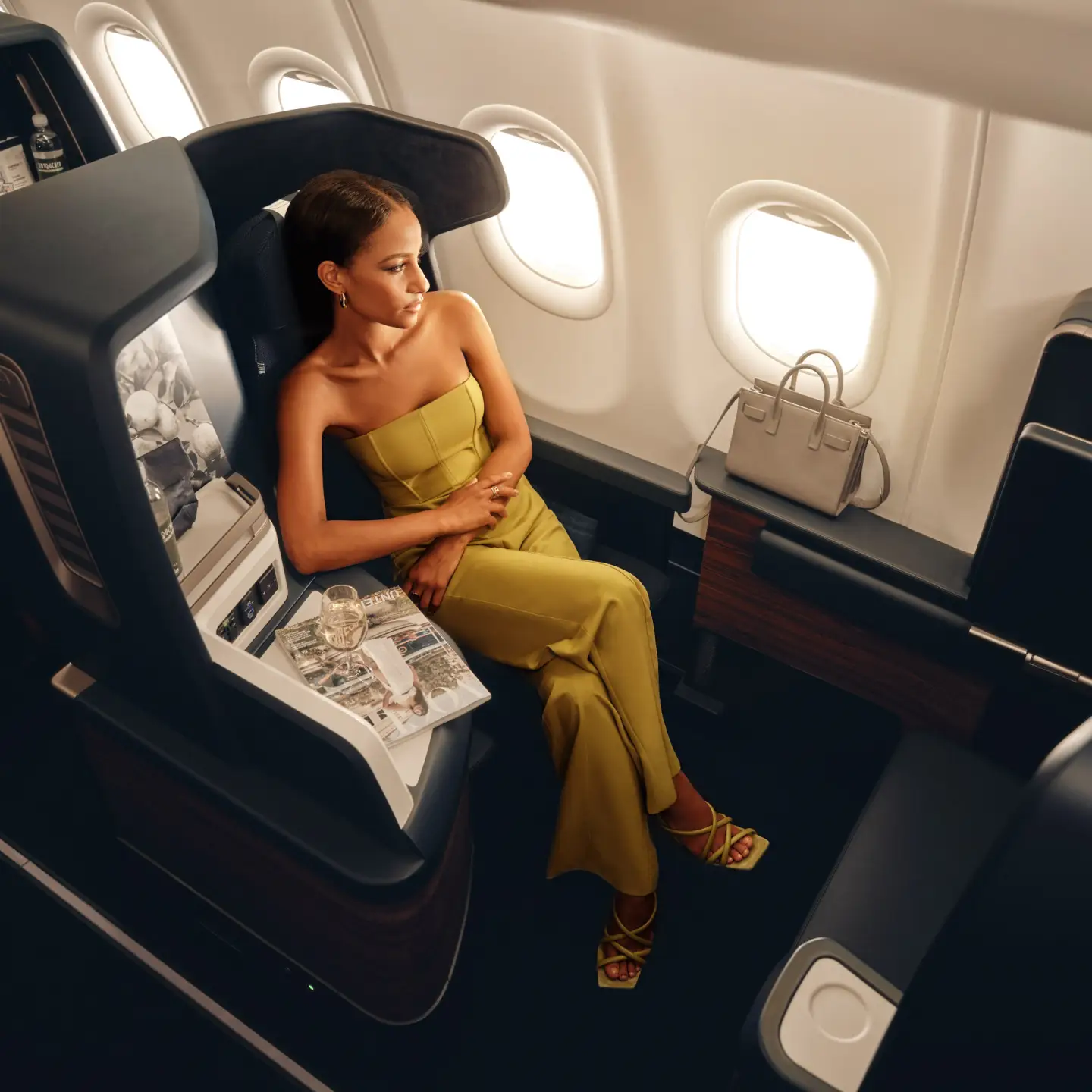 Een vrouw zit in een business class-stoel in een Condor-vliegtuig.