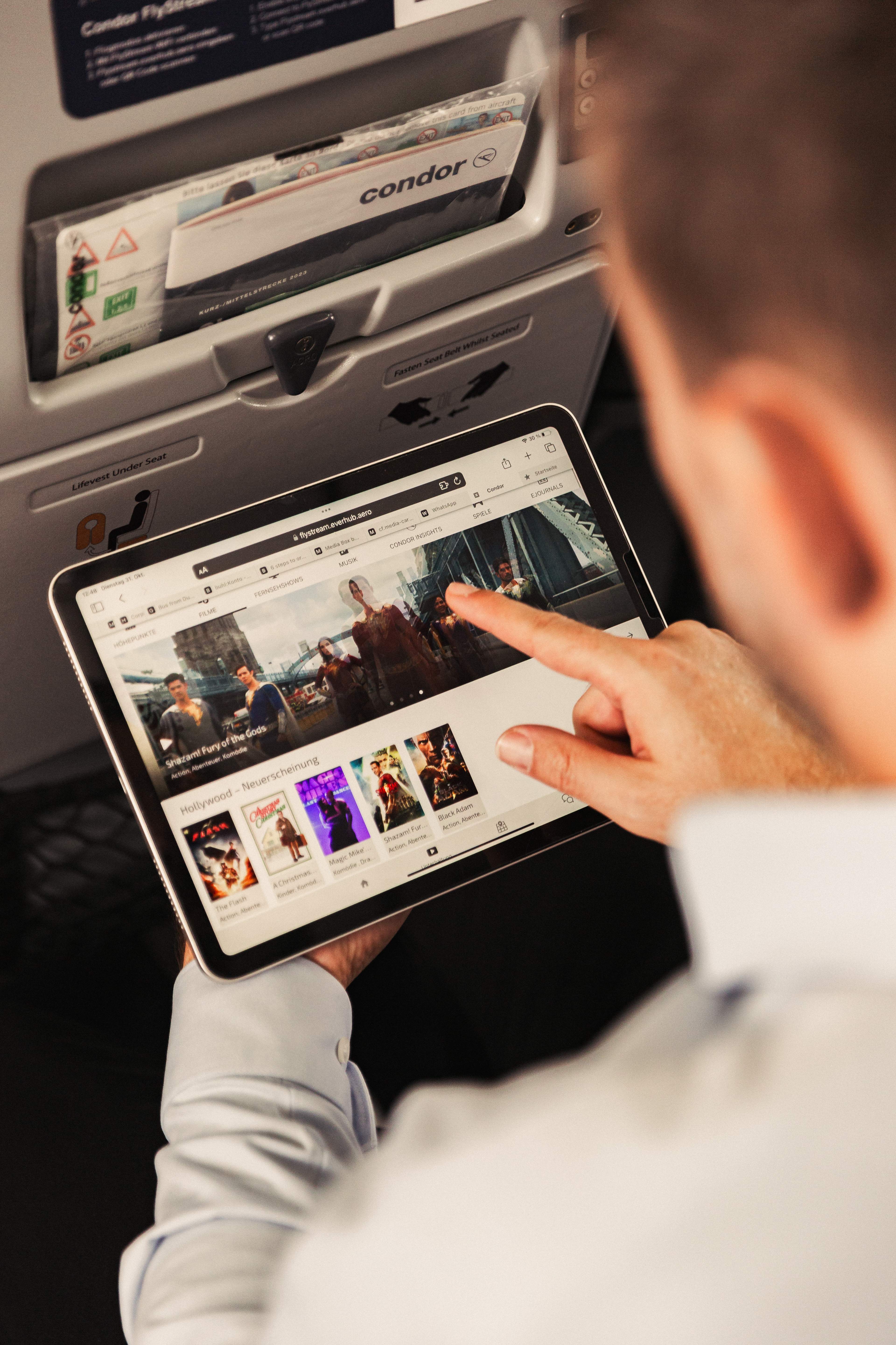 Een passagier aan boord van een vliegtuig verbindt zijn tablet met Condor FlyStream