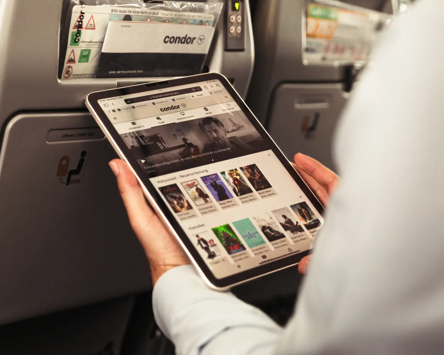 Een passagier aan boord van een vliegtuig verbindt zijn tablet met FlyStream