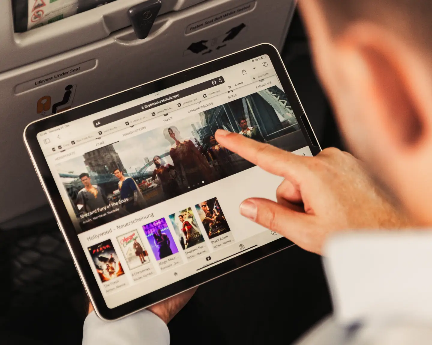 A passenger on board an aircraft is connecting his tablet to Condor FlyStream