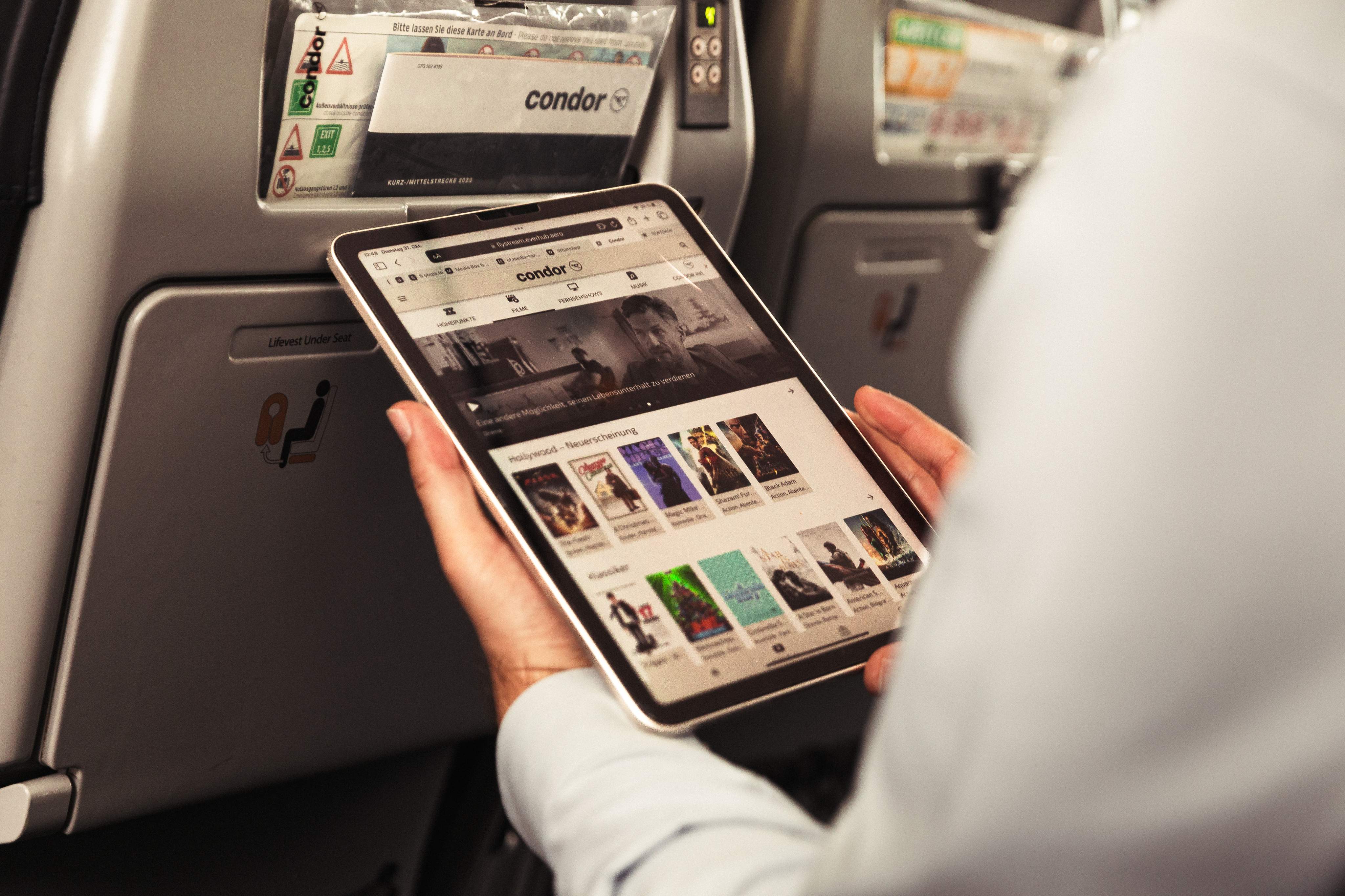 A passenger on board an airplane is connecting his tablet to FlyStream