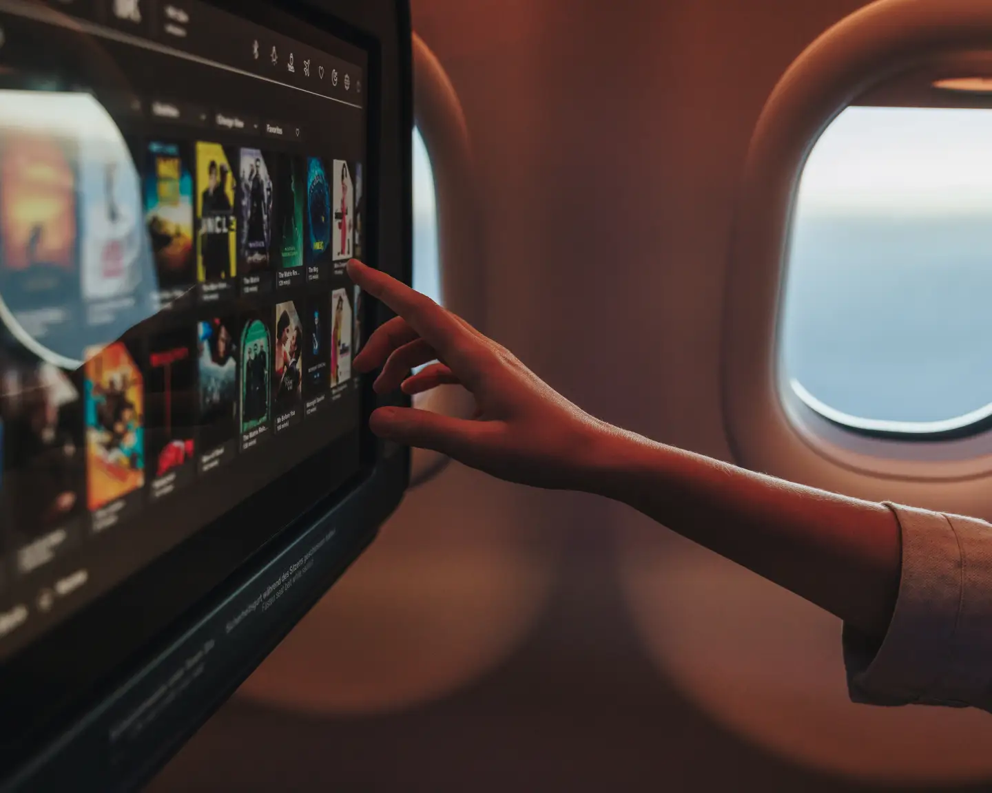 Un pasajero a bordo de un avión navega por la selección de películas disponibles en el entretenimiento a bordo en su pantalla táctil personal