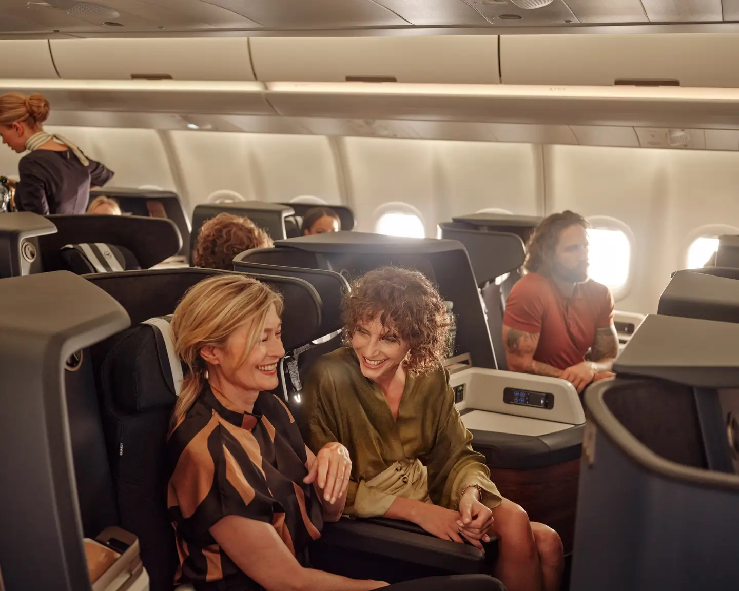 Dos mujeres risueñas están sentadas en la Business Class a bordo del A330neo de Condor.