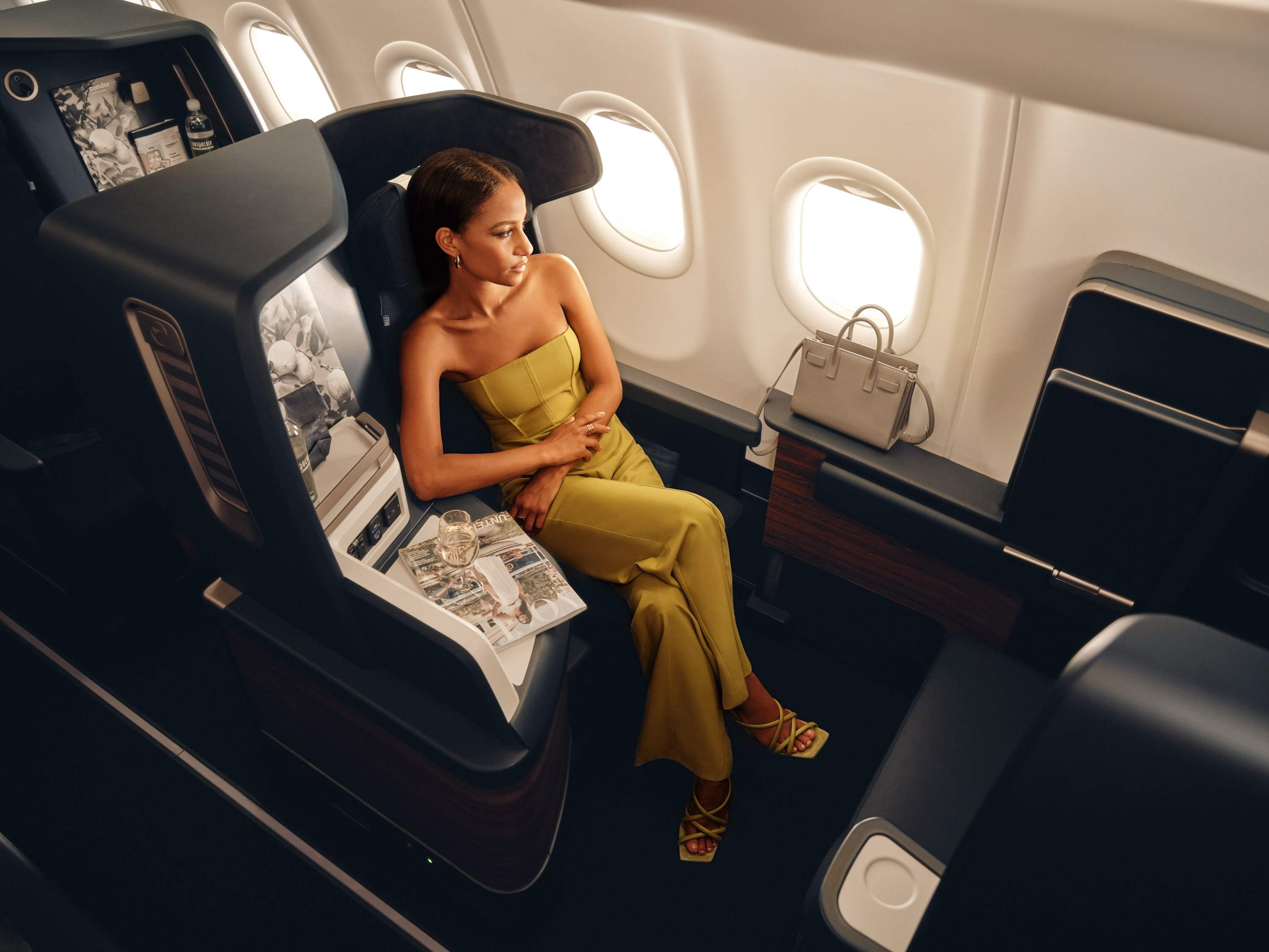 Una mujer está sentada en un asiento de Business Class en un avión de Condor.