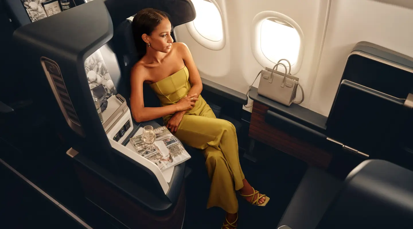 Una mujer está sentada en un asiento de Business Class en un avión de Condor.