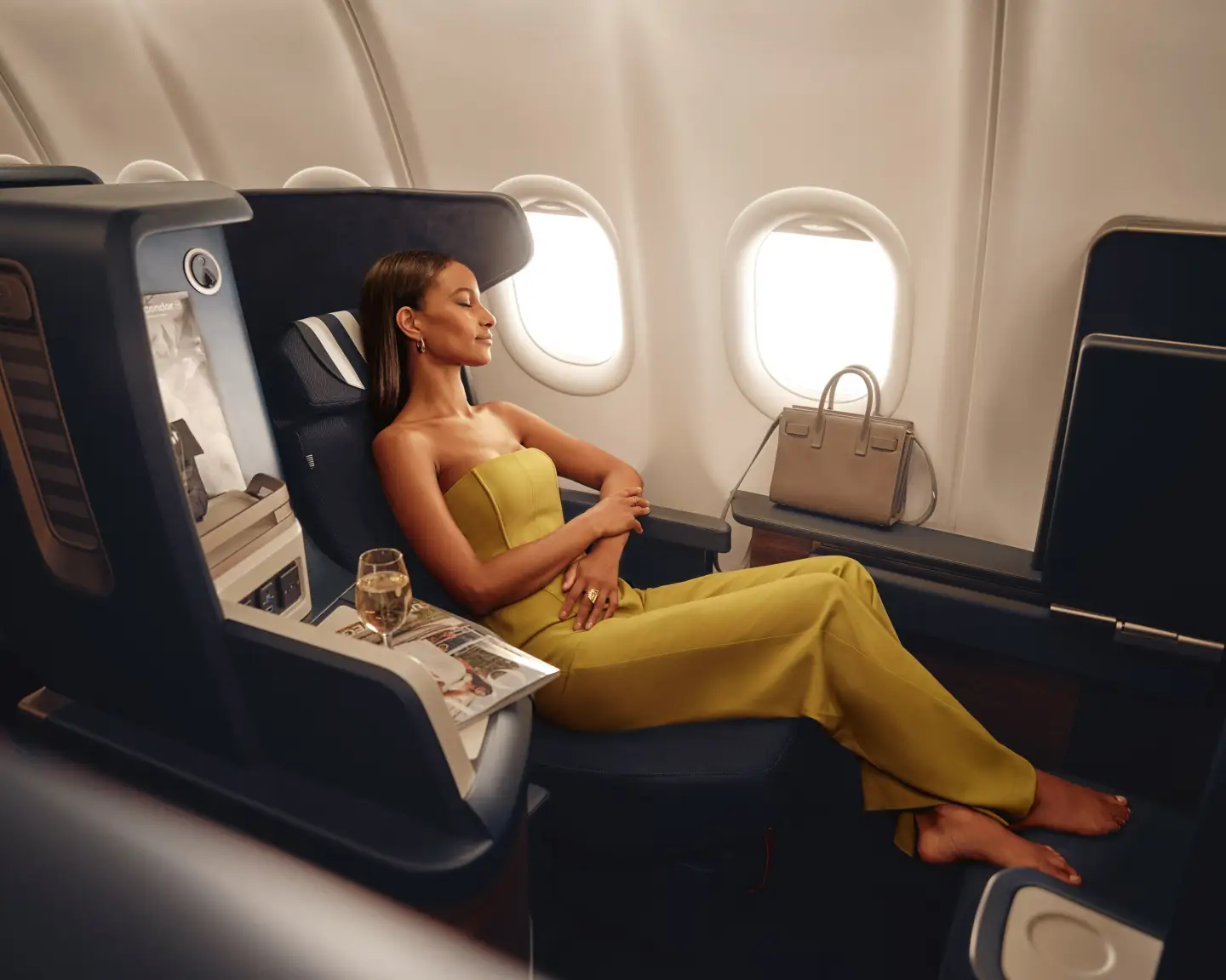 Una mujer vestida de amarillo disfruta de un Prime Seat en la Business Class de Condor.