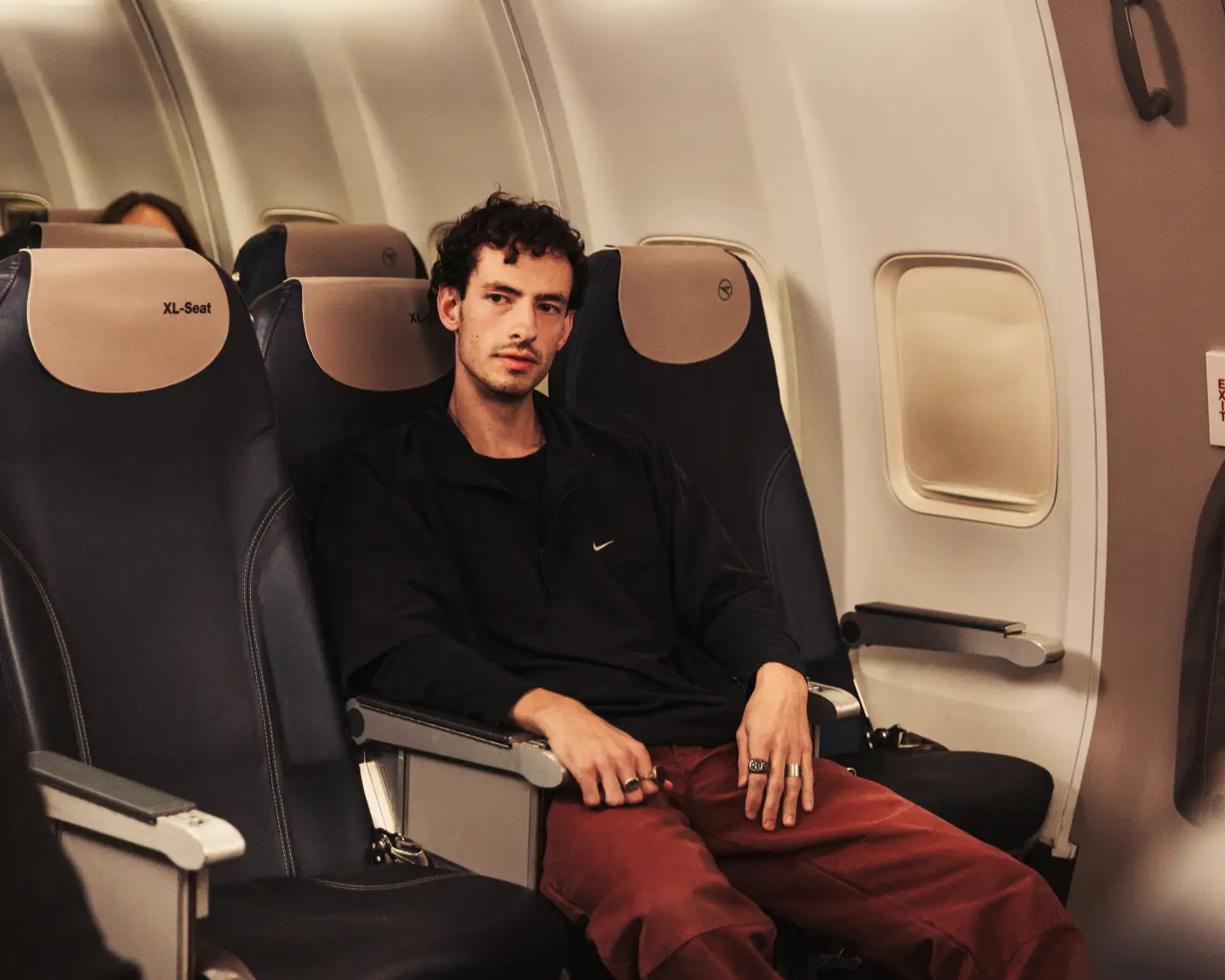 Un hombre sentado en el asiento XL de un avión y estirando las piernas.
