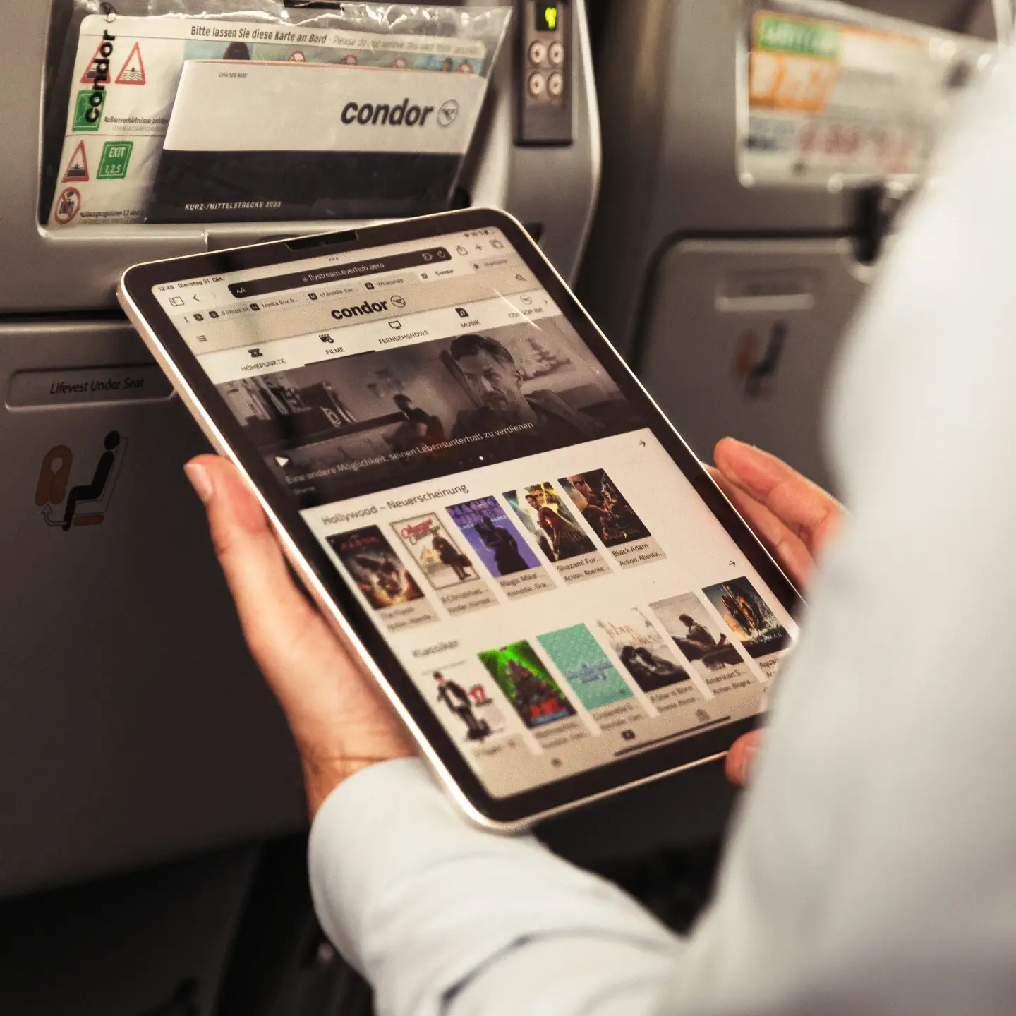 Un pasajero a bordo de un avión está conectando su tableta a FlyStream