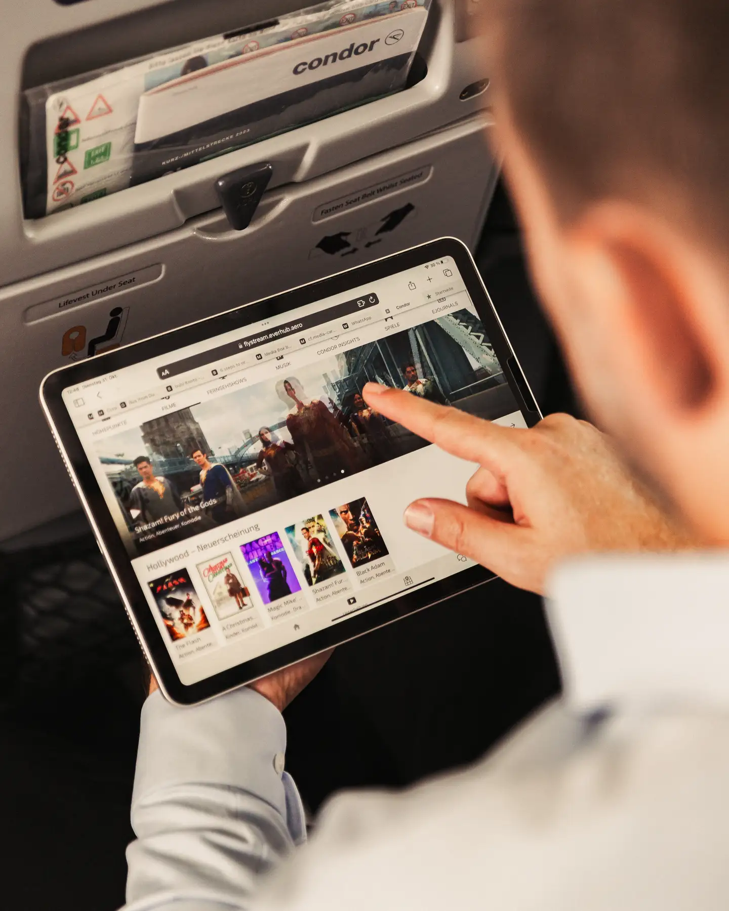 Un pasajero a bordo de un avión está conectando su tableta a Condor FlyStream