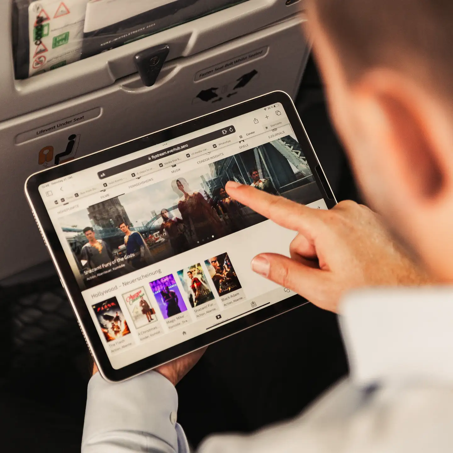 Un pasajero a bordo de un avión está conectando su tableta a Condor FlyStream