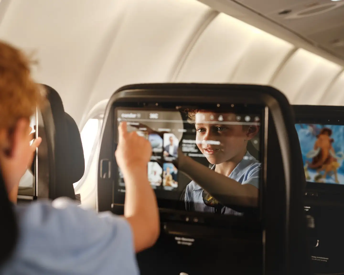 Un niño está usando el sistema de entretenimiento del avión de Condor.