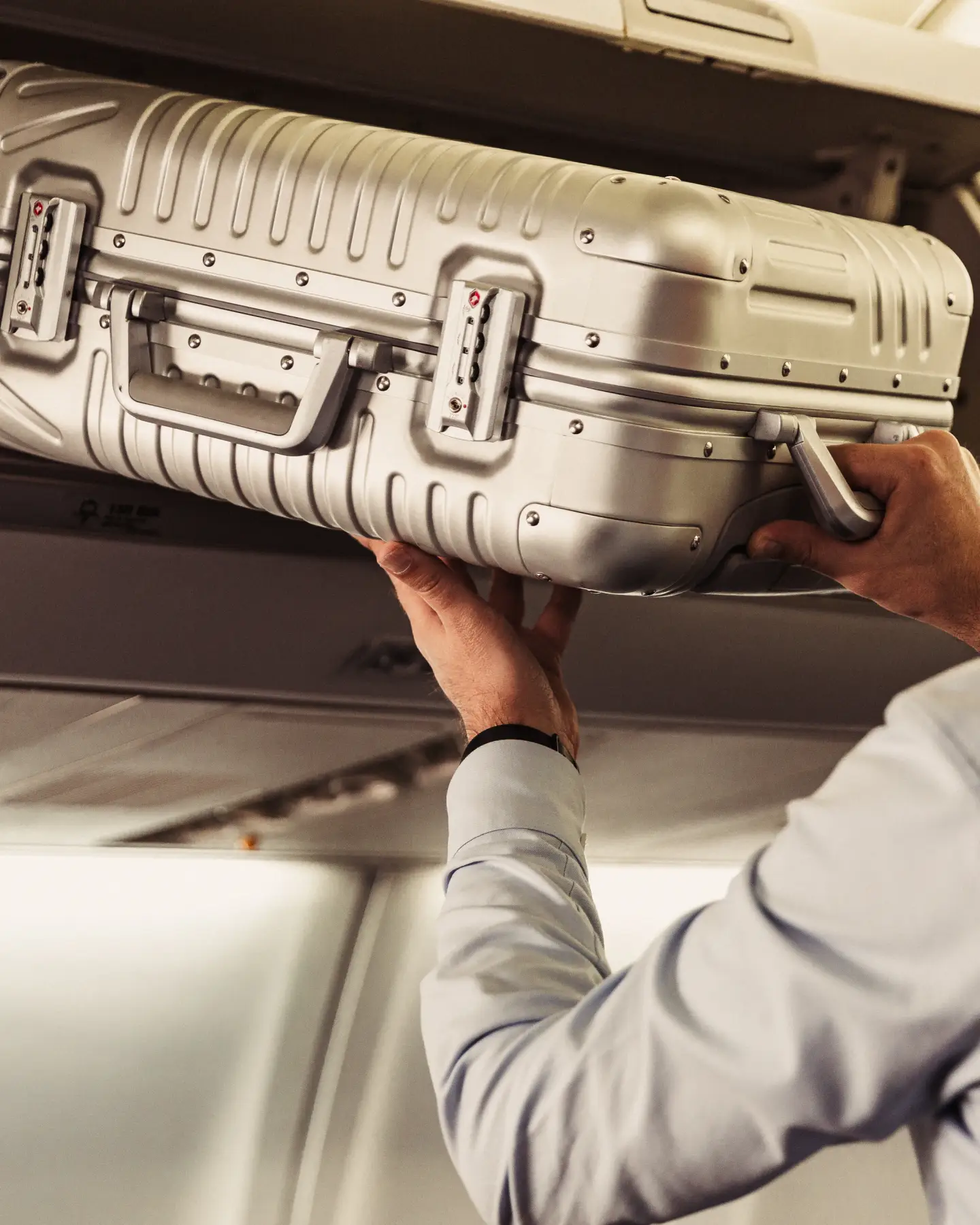 Un homme récupère sa valise à main dans le compartiment au-dessus de son siège