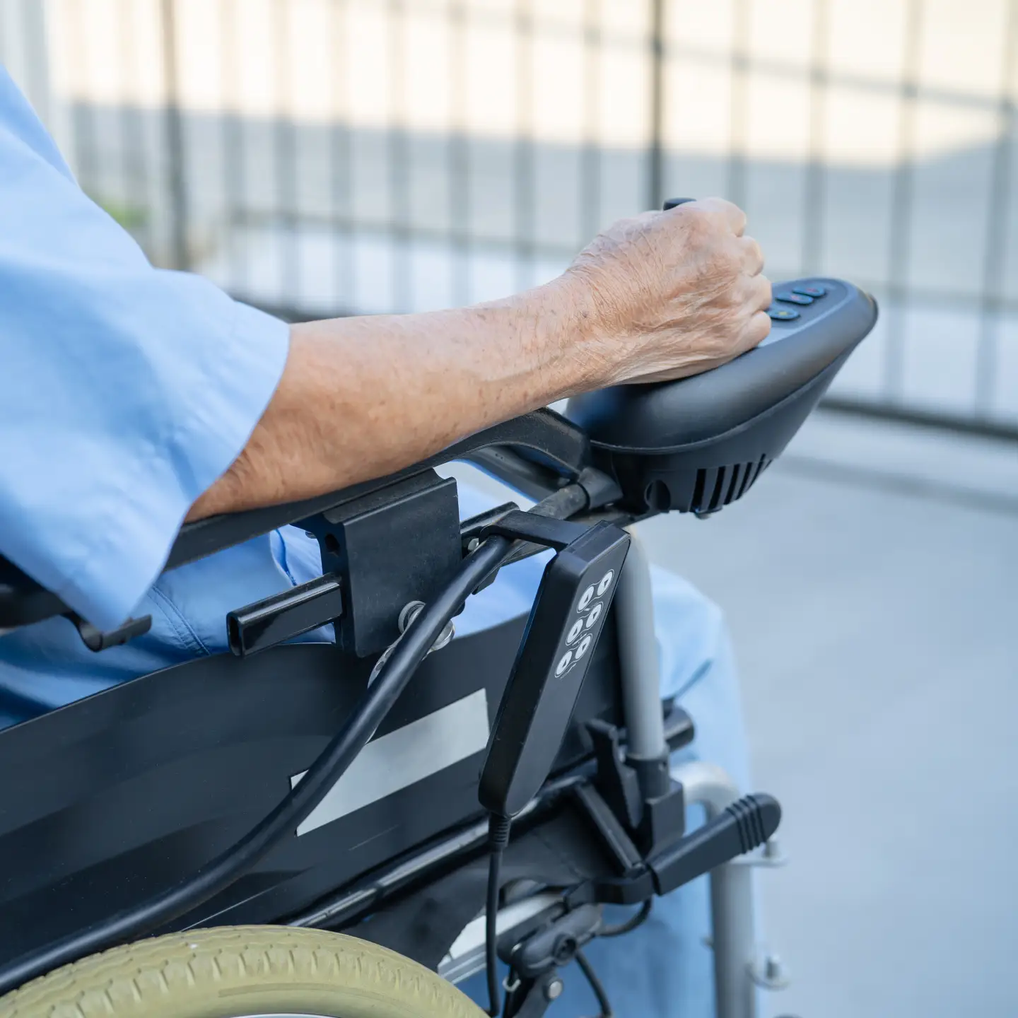Close-up van een oudere persoon die een elektrische rolstoel bedient met behulp van een bedieningspaneel.