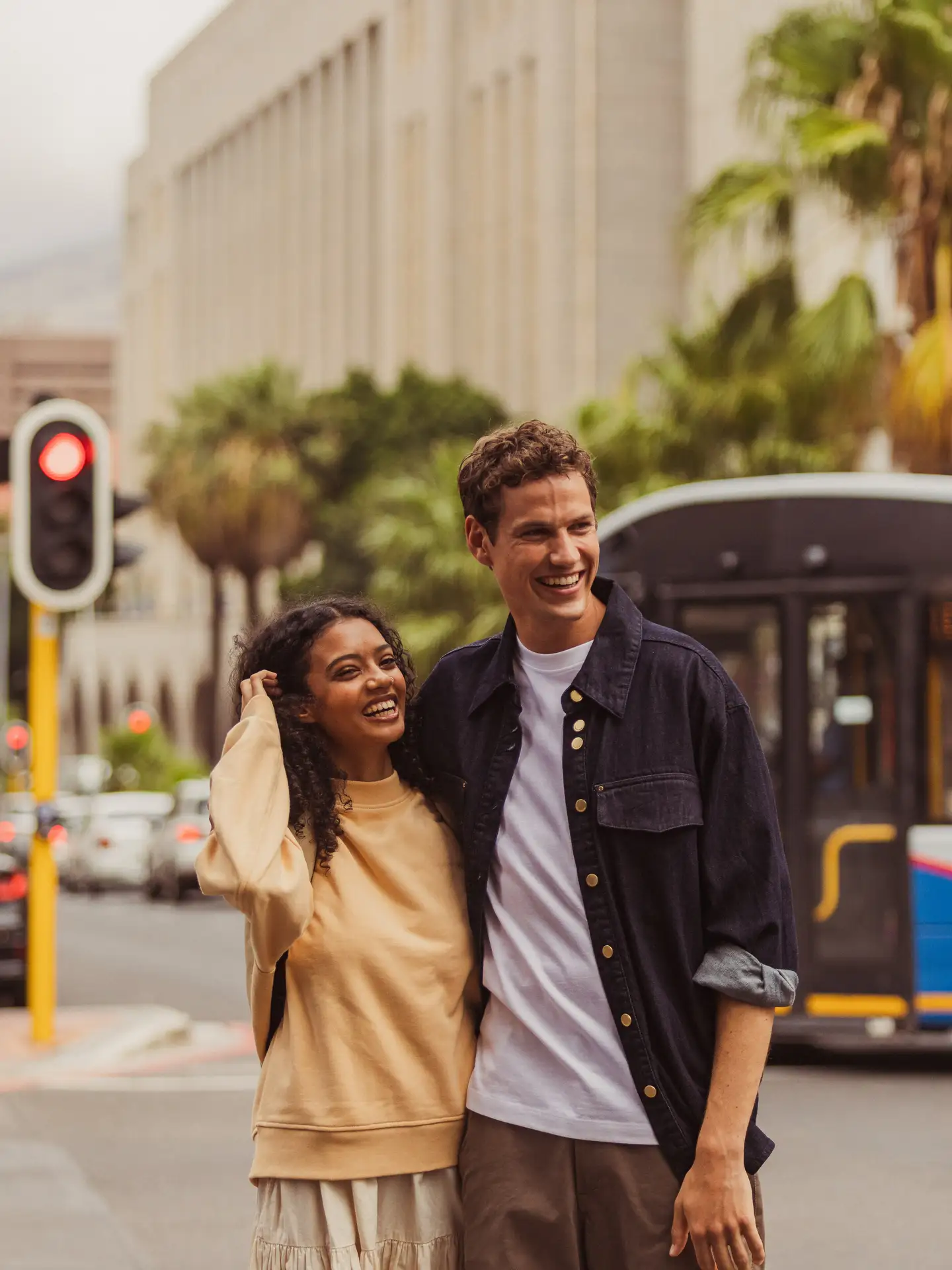 Escena callejera con una pareja joven en una ciudad estadounidense, sonriendo y abrazándose.