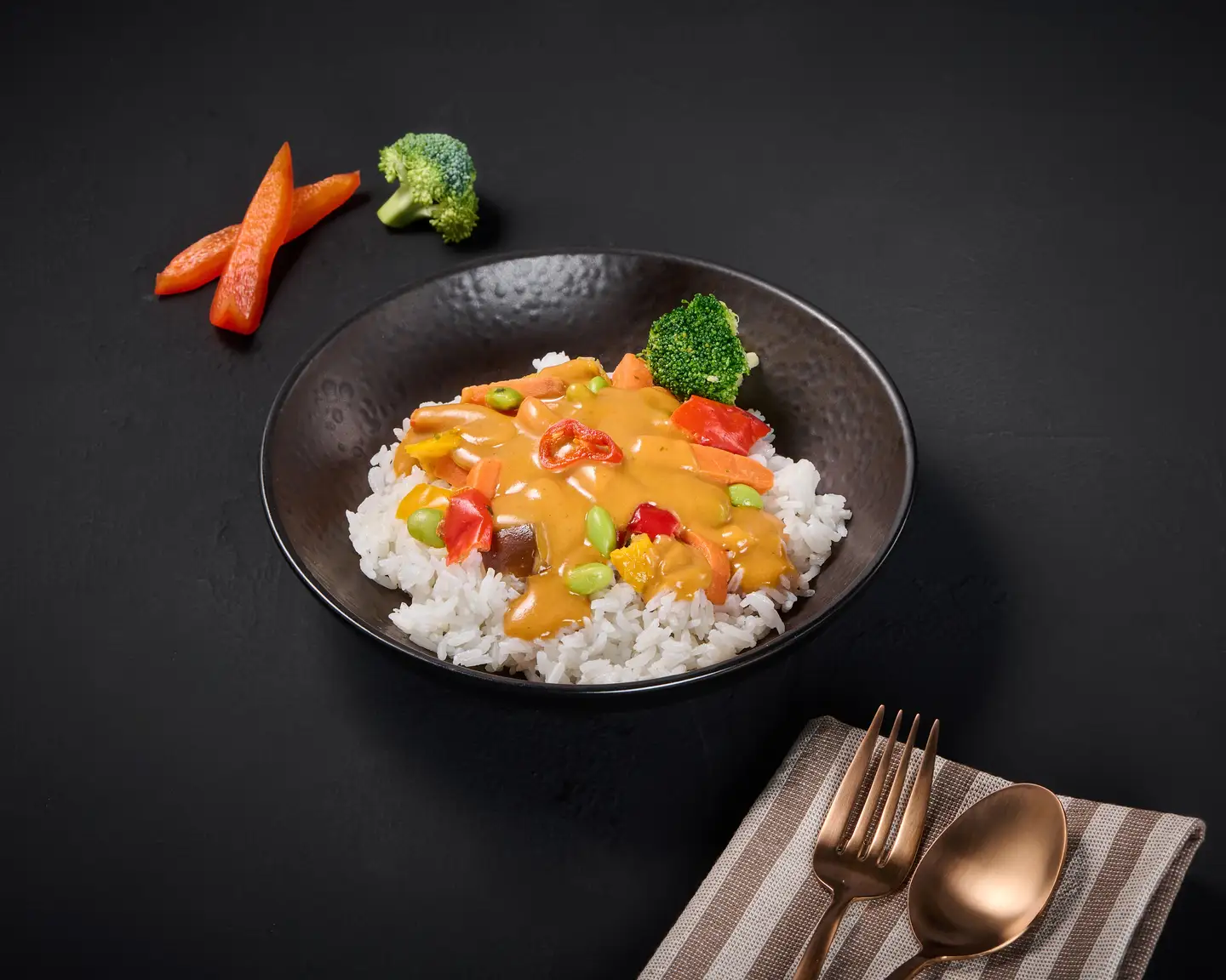 Curry con verduras y pollo en salsa amarilla y arroz, servido en un plato