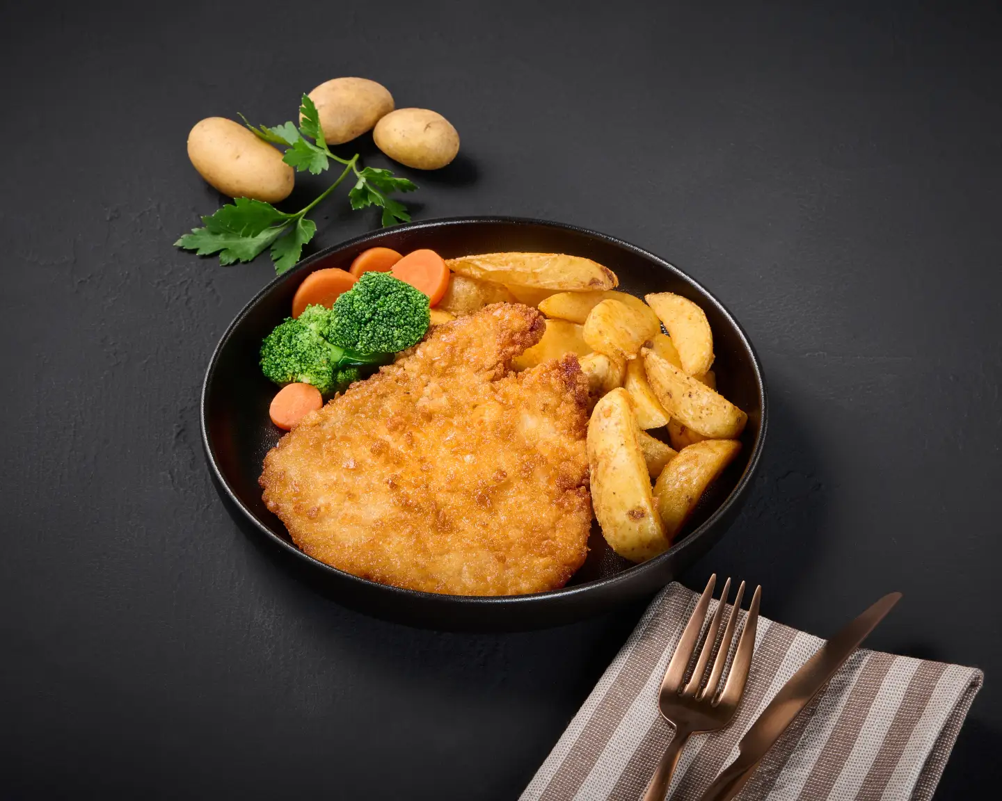 Schnitzel met aardappelpartjes geserveerd op een bord