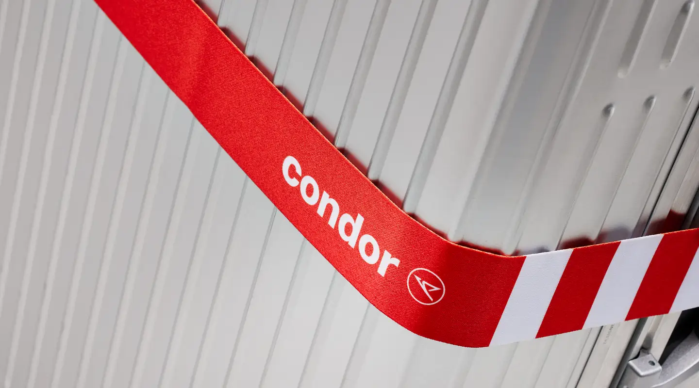 una maleta de viaje con una correa alrededor en el color pasión de Condor