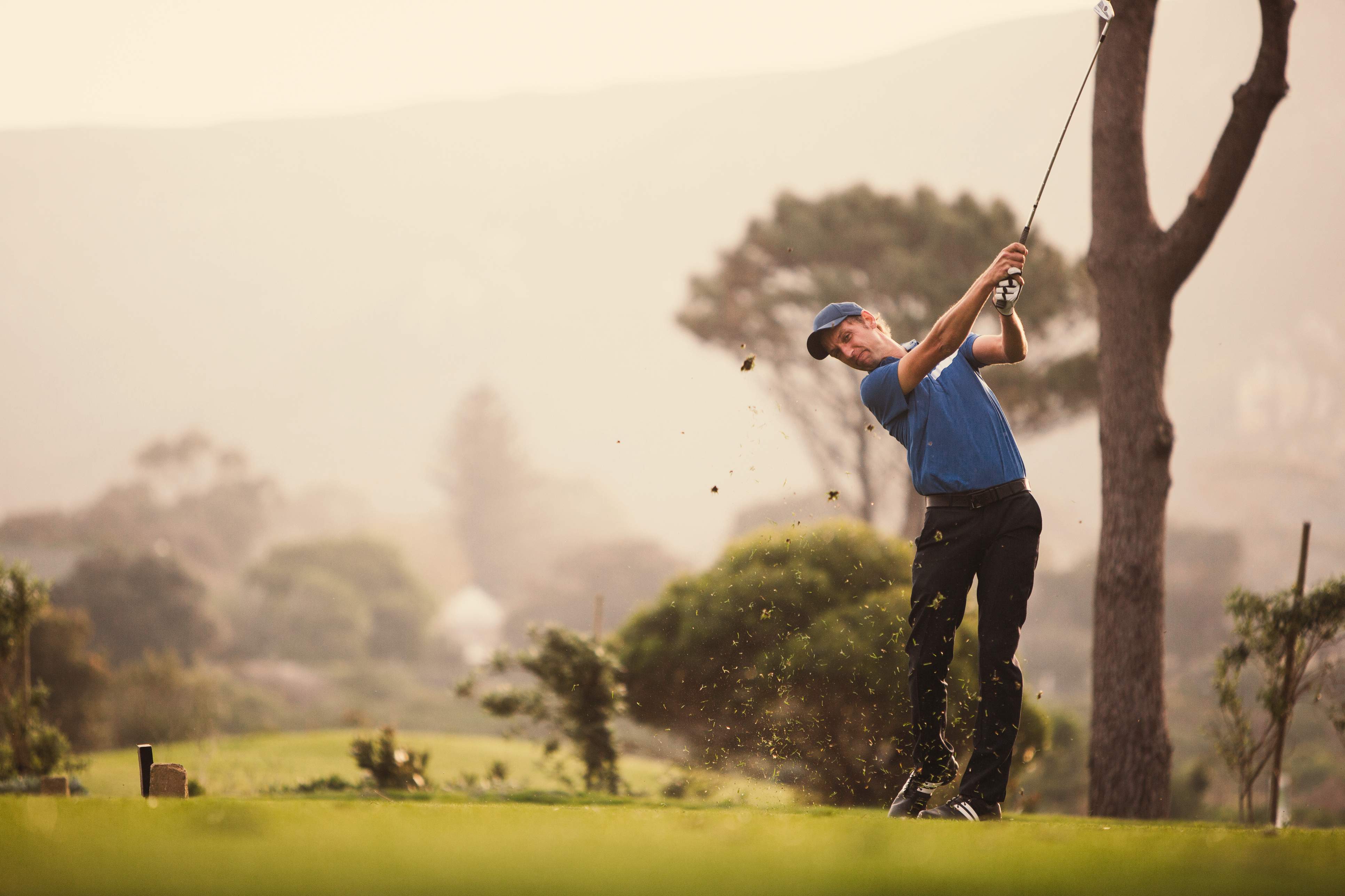 A young male golfer swings his driver for his t-shot.