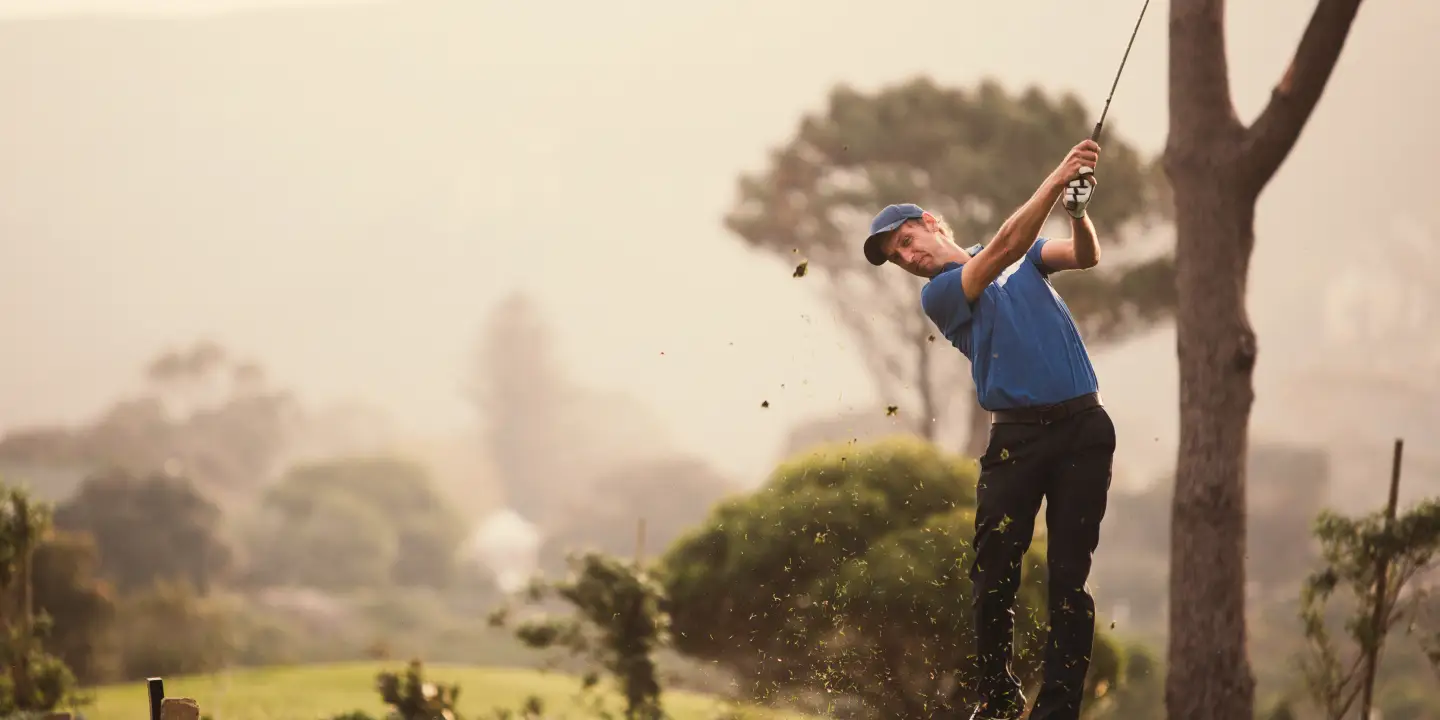 A young male golfer swings his driver for his t-shot.