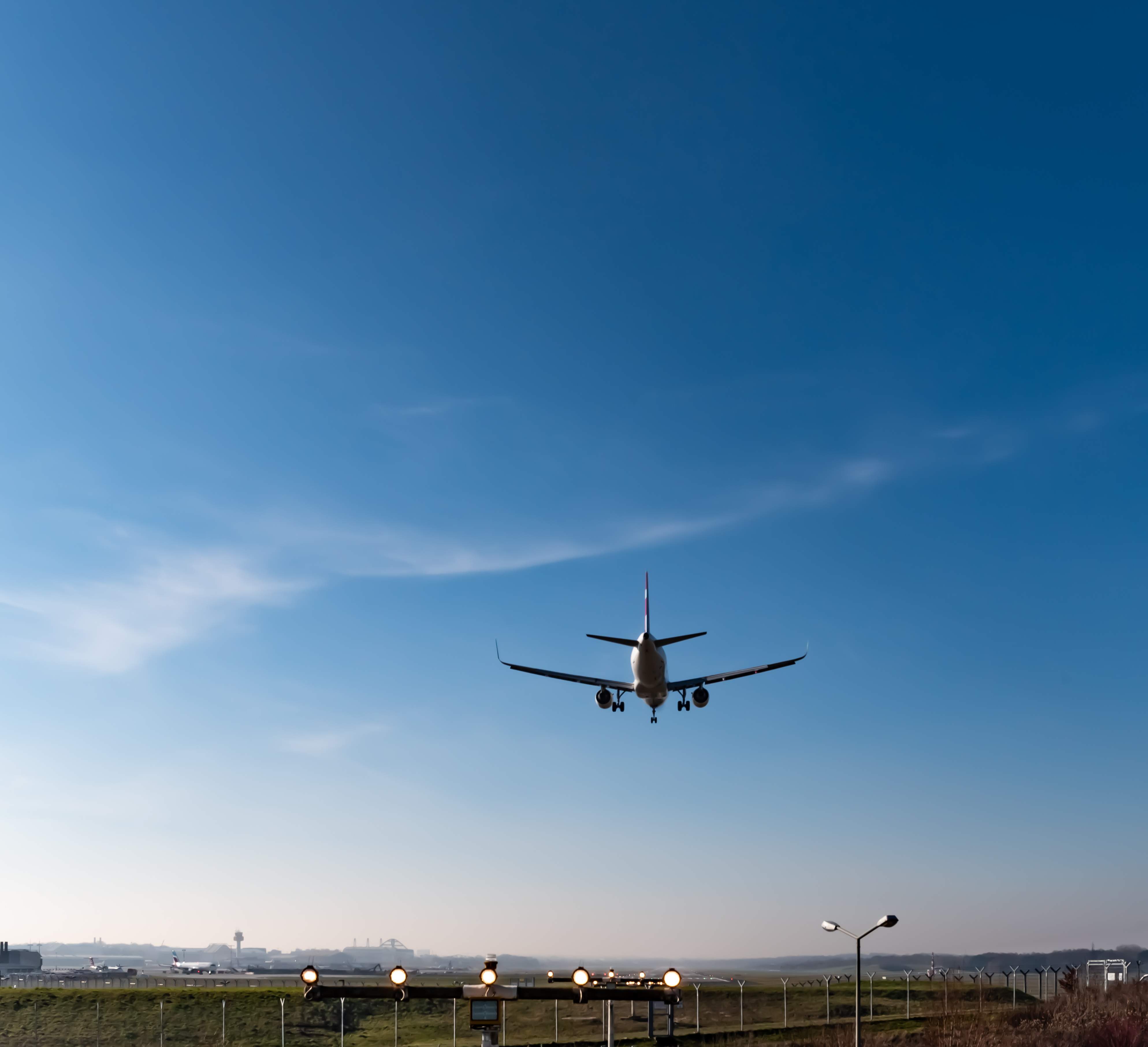 Flugzeug im Landeanflug auf den Flughafen Berlin Brandenburg (BER) vor klarem blauem Himmel.