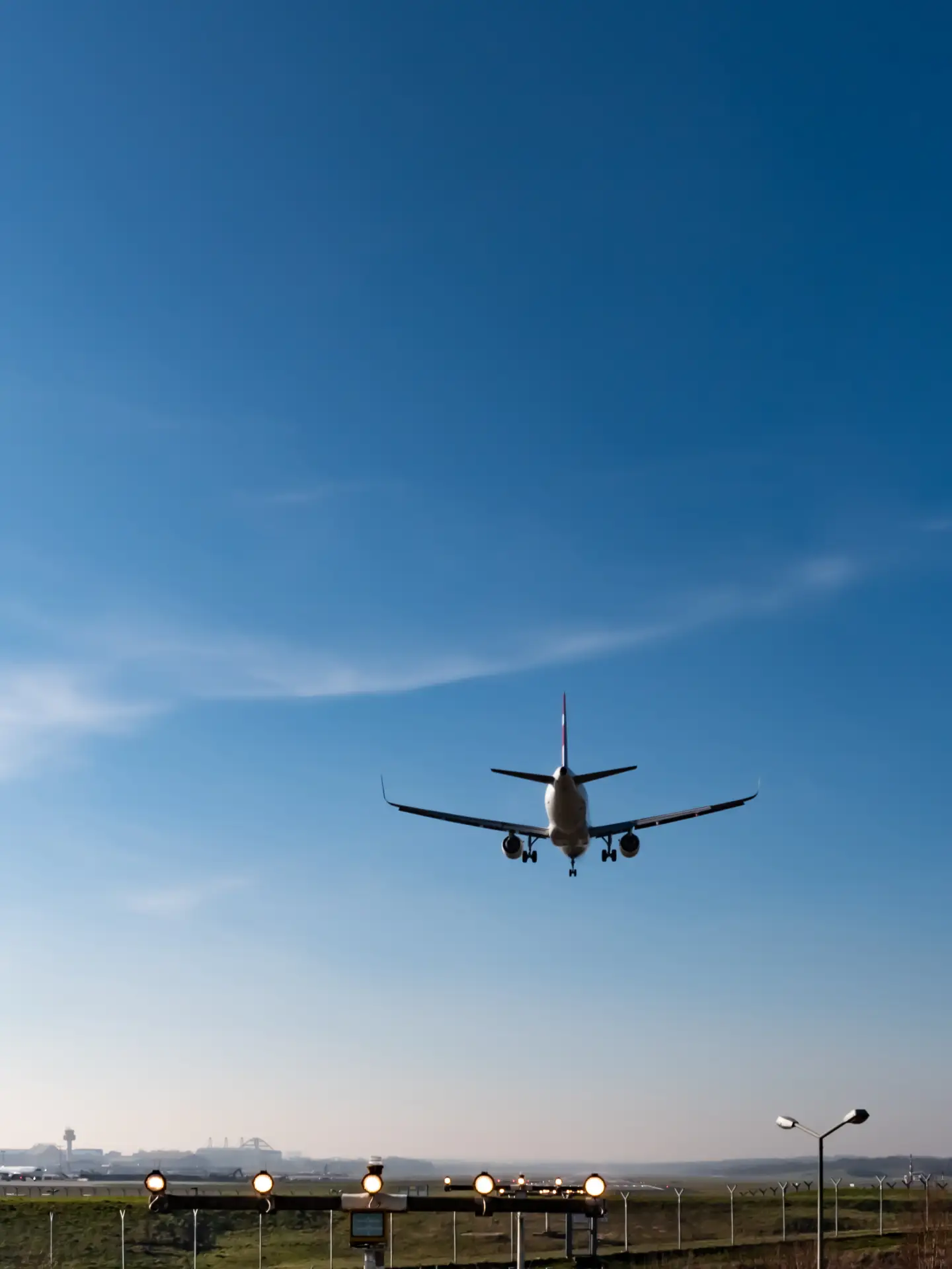 Flugzeug im Landeanflug auf den Flughafen Berlin Brandenburg (BER) vor klarem blauem Himmel.