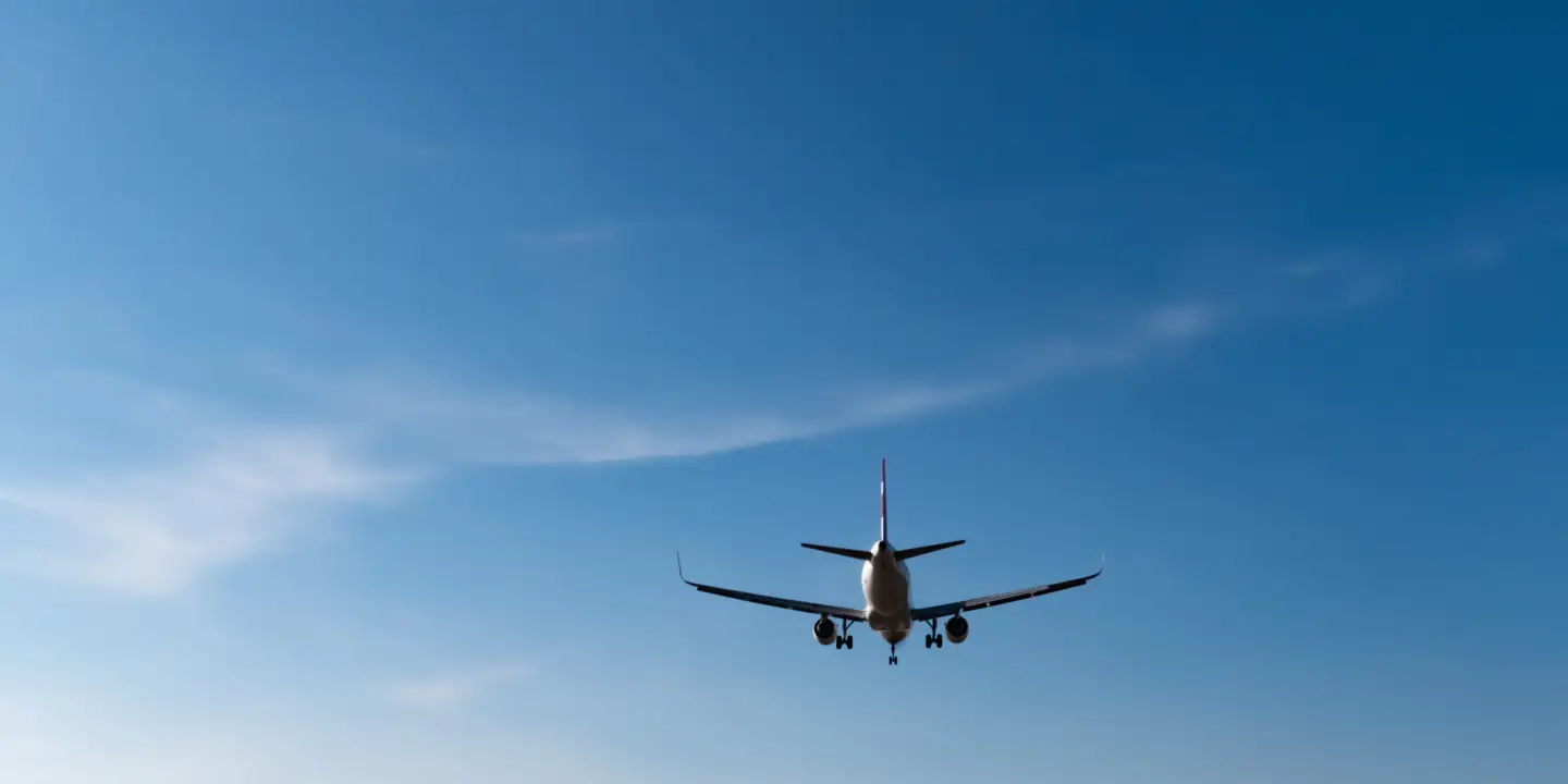 Flugzeug im Landeanflug auf den Flughafen Berlin Brandenburg (BER) vor klarem blauem Himmel.