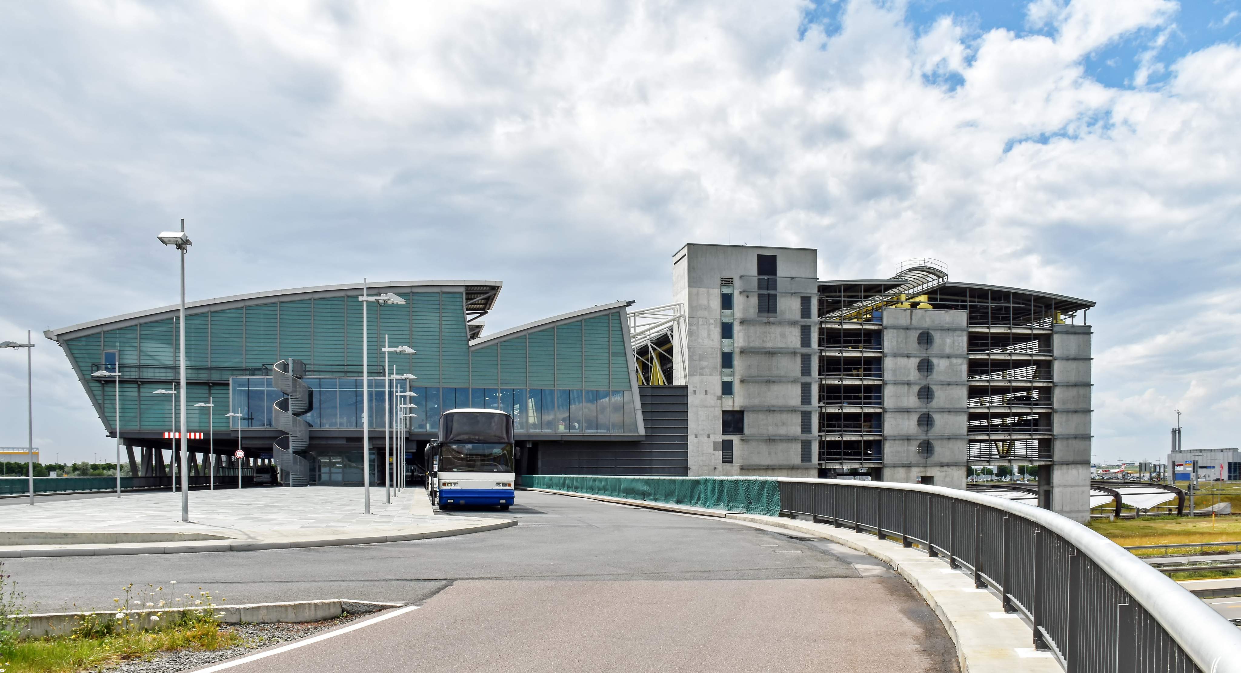 Außenansicht des Flughafens Leipzig/Halle mit Terminalgebäude, Parkhaus und Busvorfahrt.