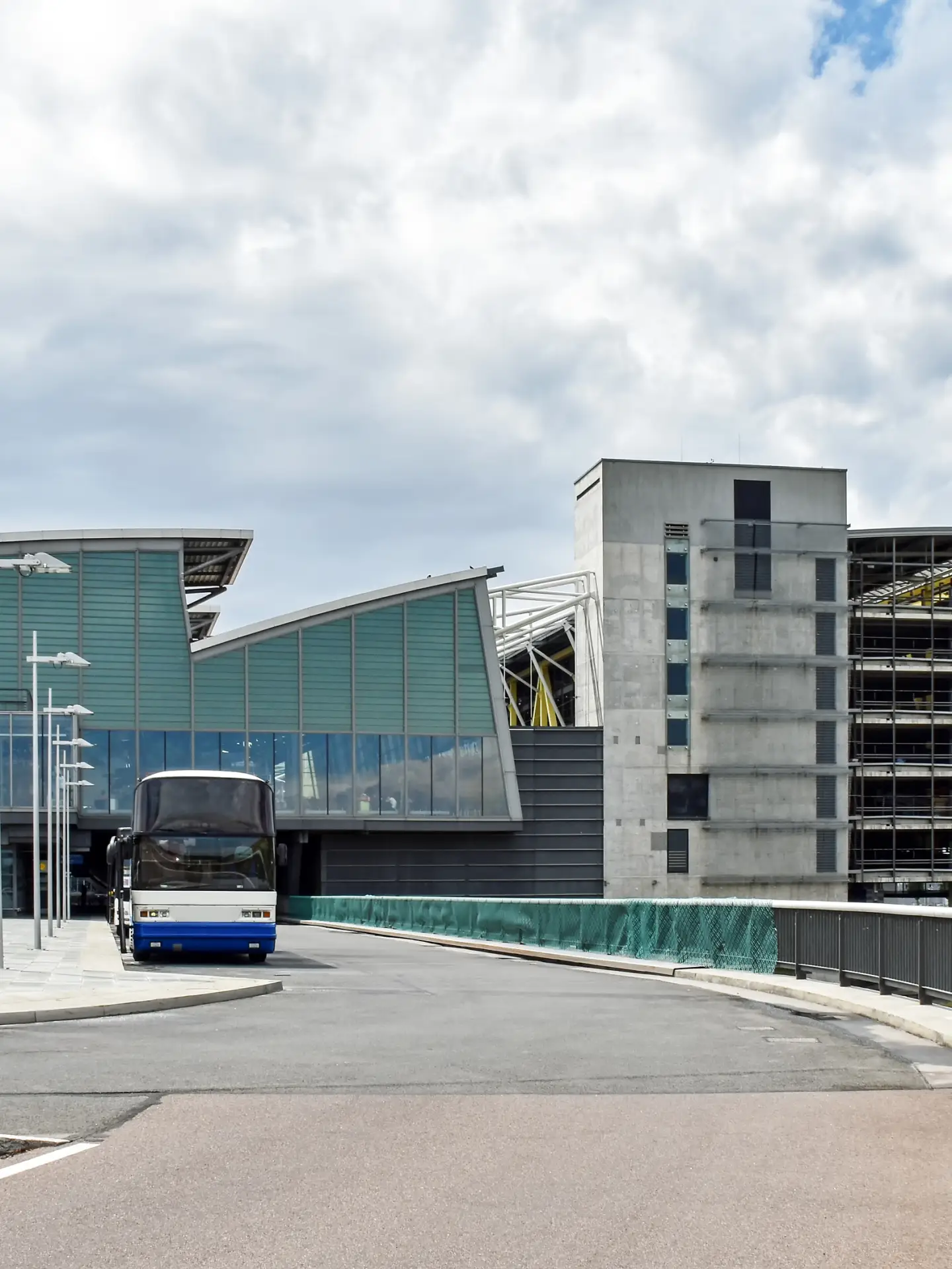 Außenansicht des Flughafens Leipzig/Halle mit Terminalgebäude, Parkhaus und Busvorfahrt.