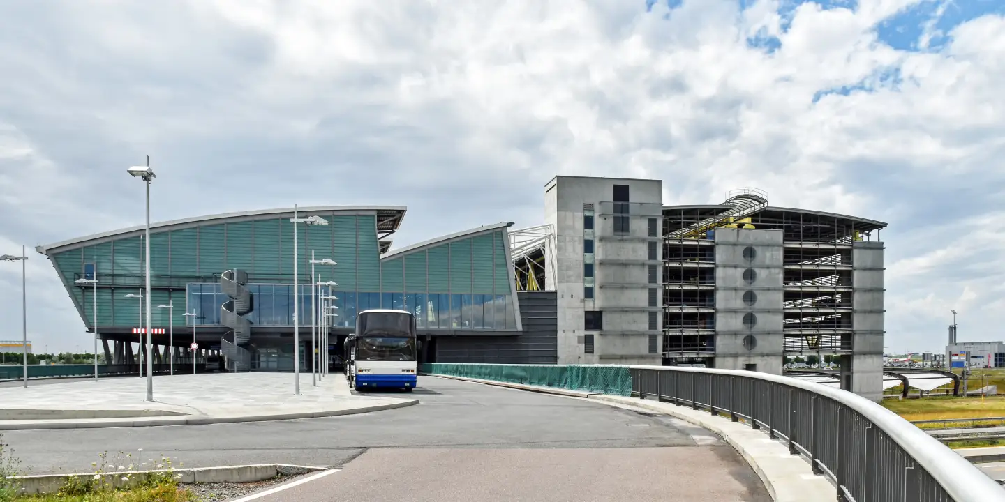 Außenansicht des Flughafens Leipzig/Halle mit Terminalgebäude, Parkhaus und Busvorfahrt.