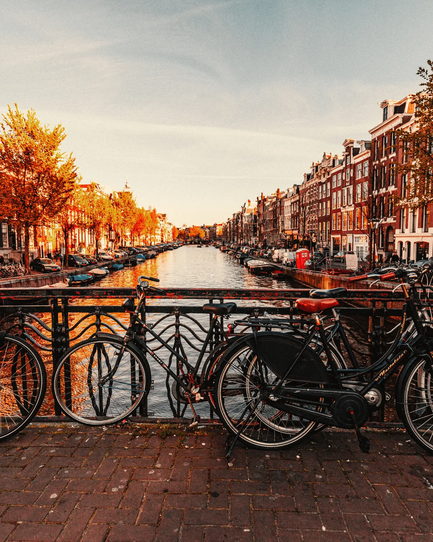 A cityscape of Amsterdam with plenty of bicycle parking spaces by a typical canal and a bridge on a sunny day