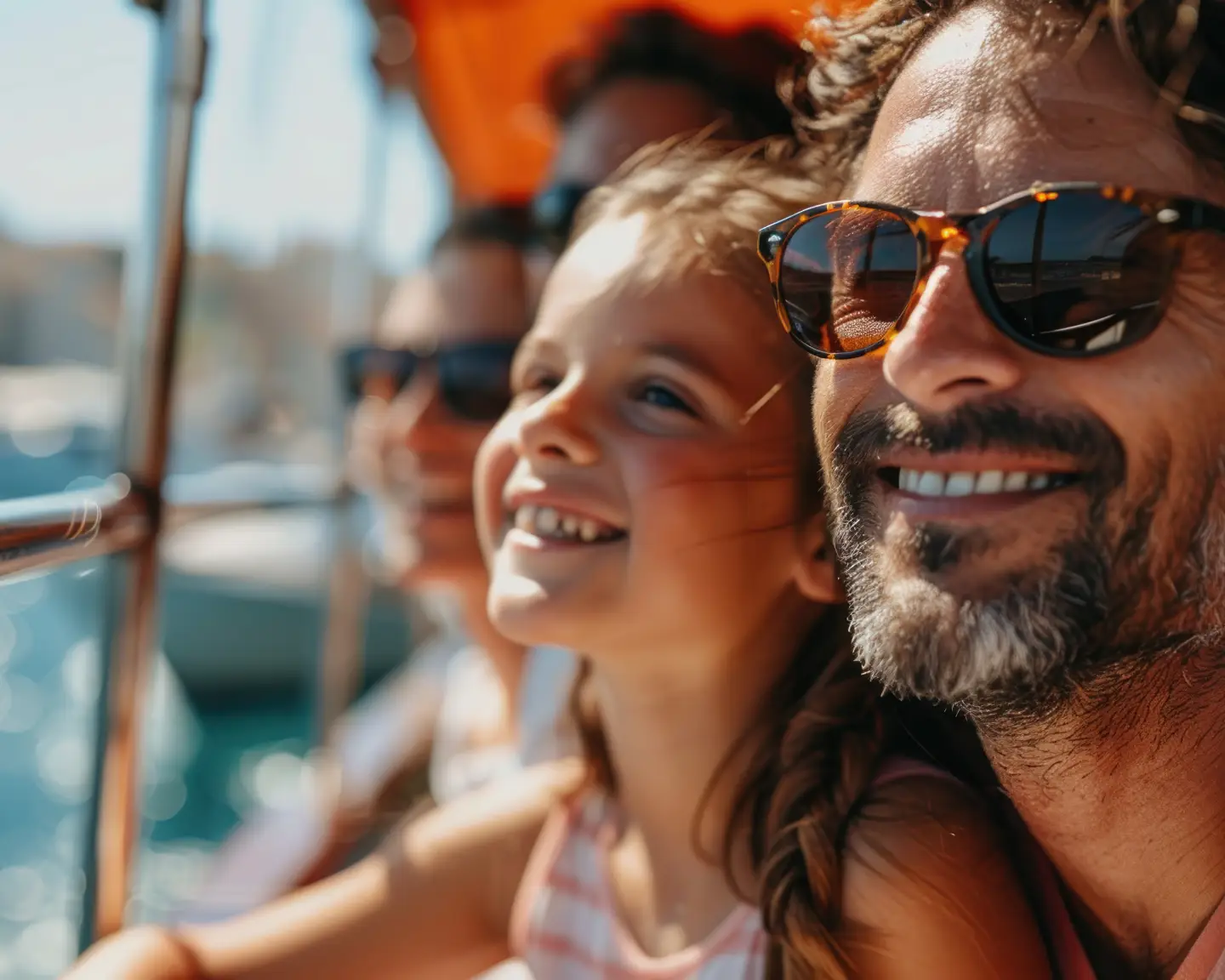 A family enjoys a boat tour together in sunny weather and looks at the water with a relaxed expression.