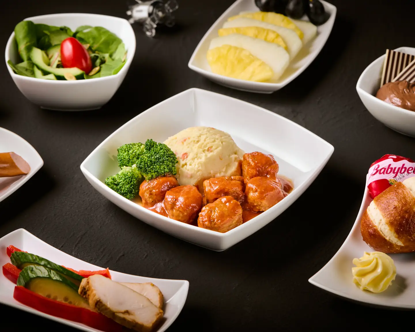 Business Class Menü mit warmem Hauptgericht, Salat, Dessert, Obst und Brot an Bord eines Condor Fluges.