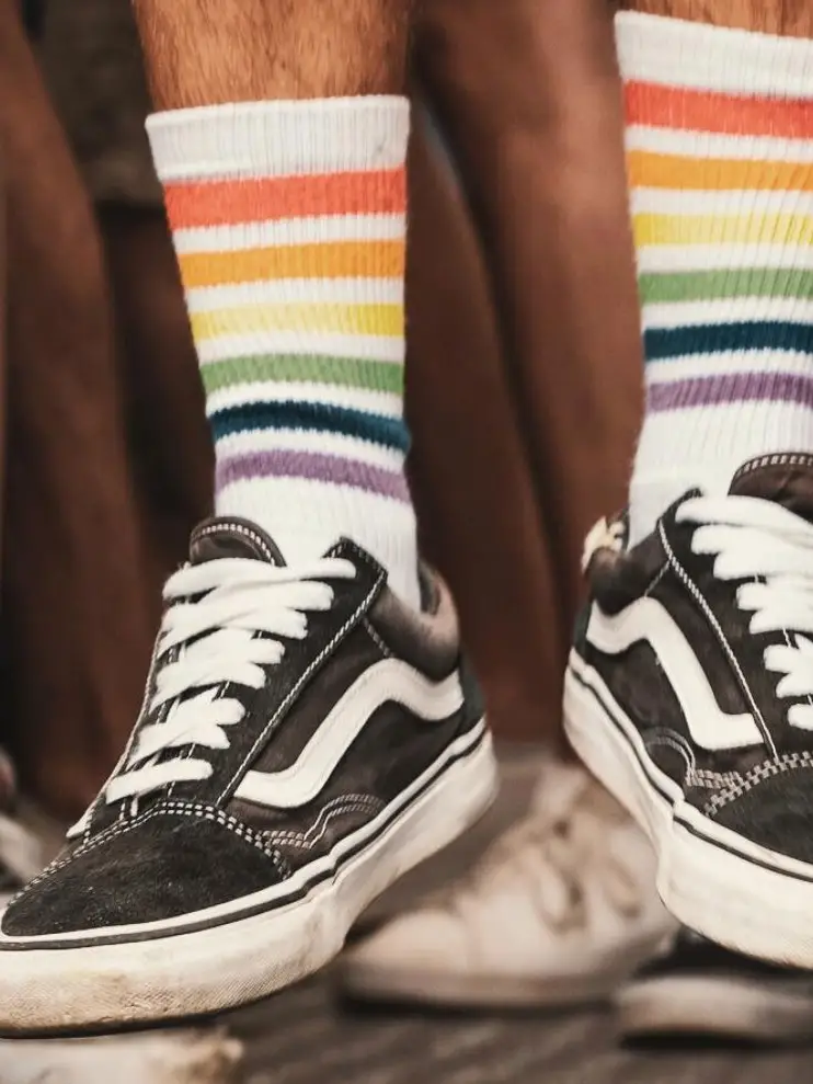 Menschen tragen Sneaker und Regenbogen-Socken während einer Pride-Veranstaltung als Zeichen für Vielfalt, Gleichberechtigung und die LGBTIQ+-Community.