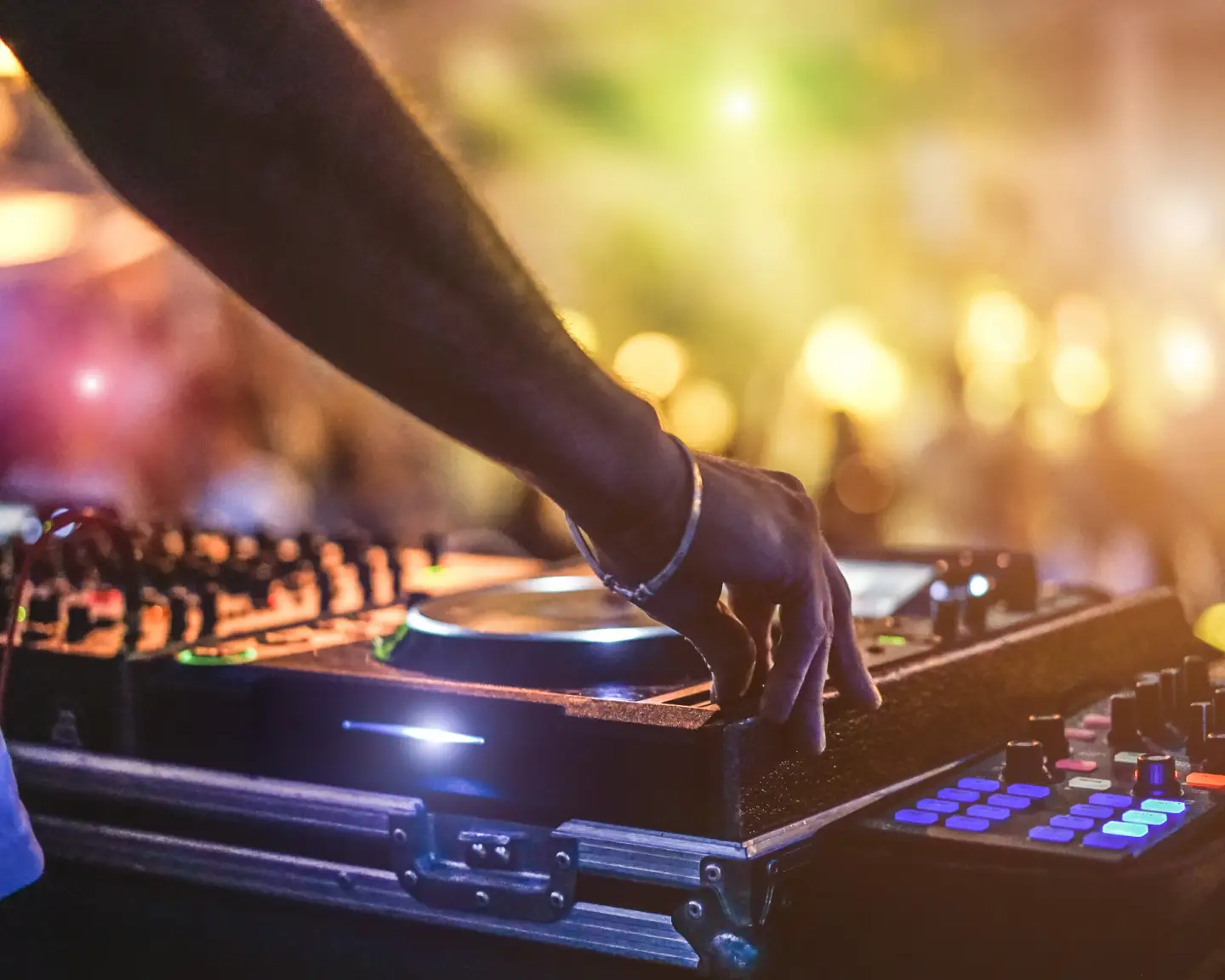 Dj mixing outdoor at beach party festival with crowd of people in background - Summer nightlife view of disco club outside - Soft focus on hand - Fun ,youth,entertainment and fest concept