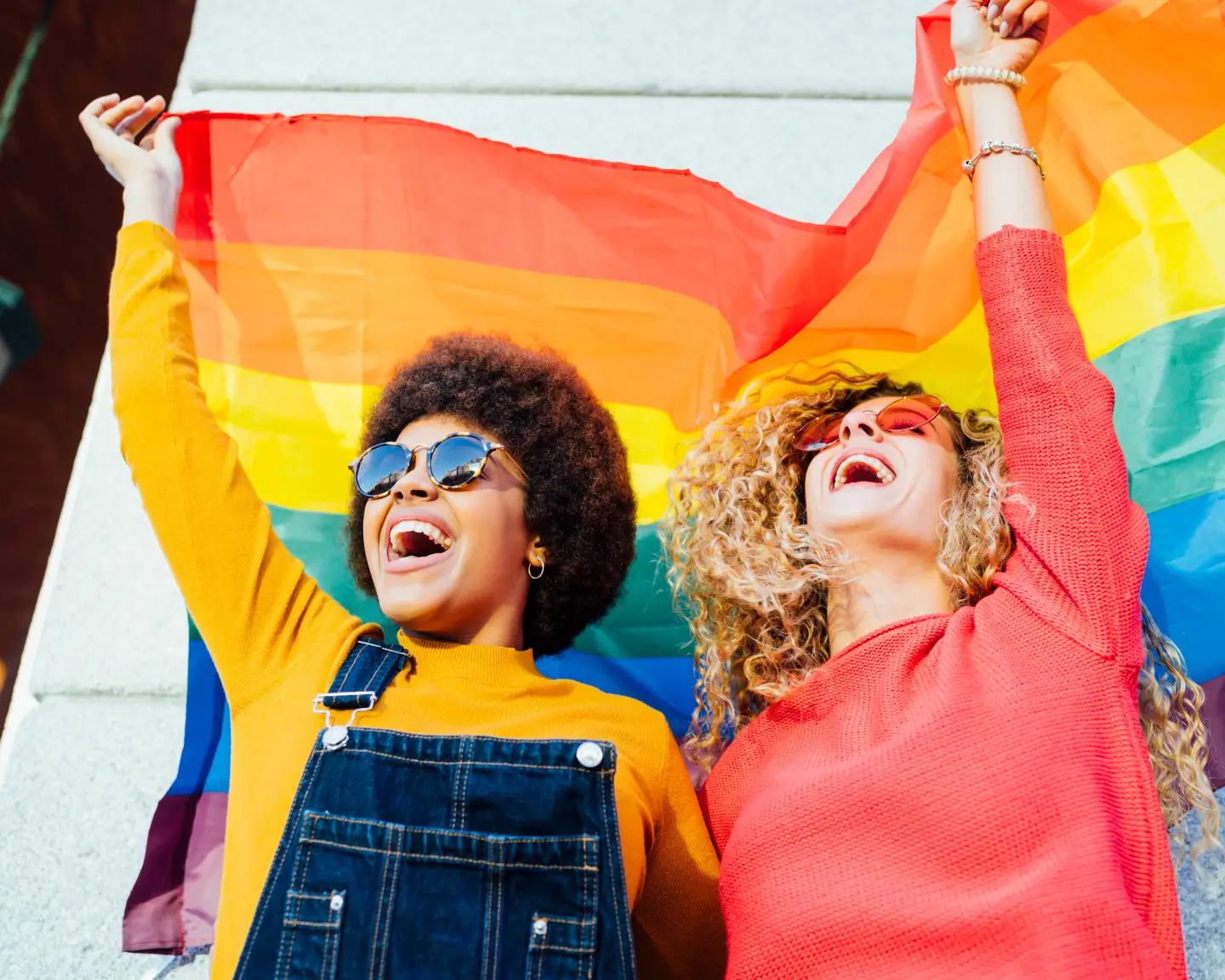 Zwei Freundinnen, die in der Stadt unterwegs sind, schwenken eine Regenbogenflagge.