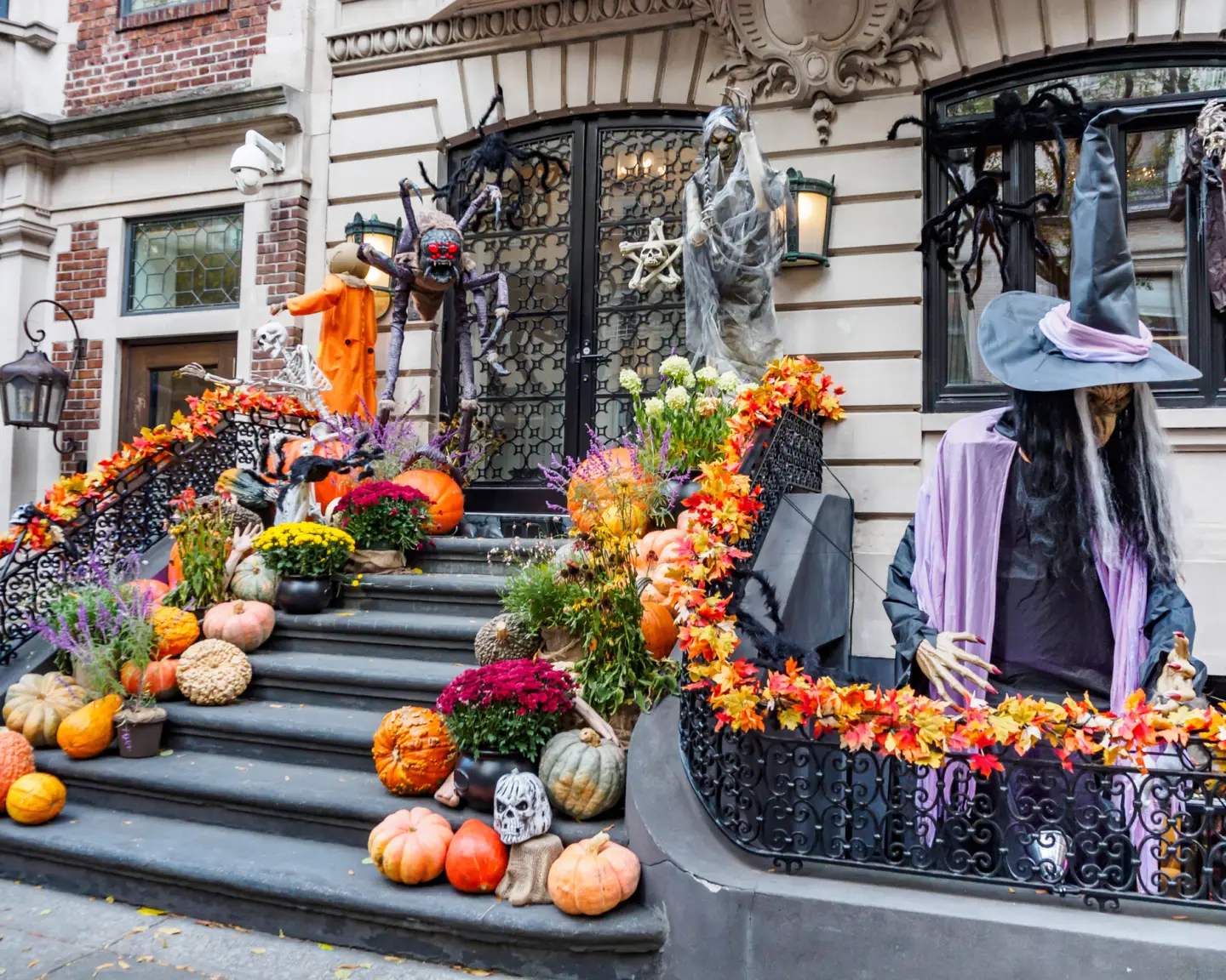 Aufwendig dekoriertes Stadthaus mit Kürbissen, Skeletten, Spinnen und einer Hexenfigur zu Halloween.
