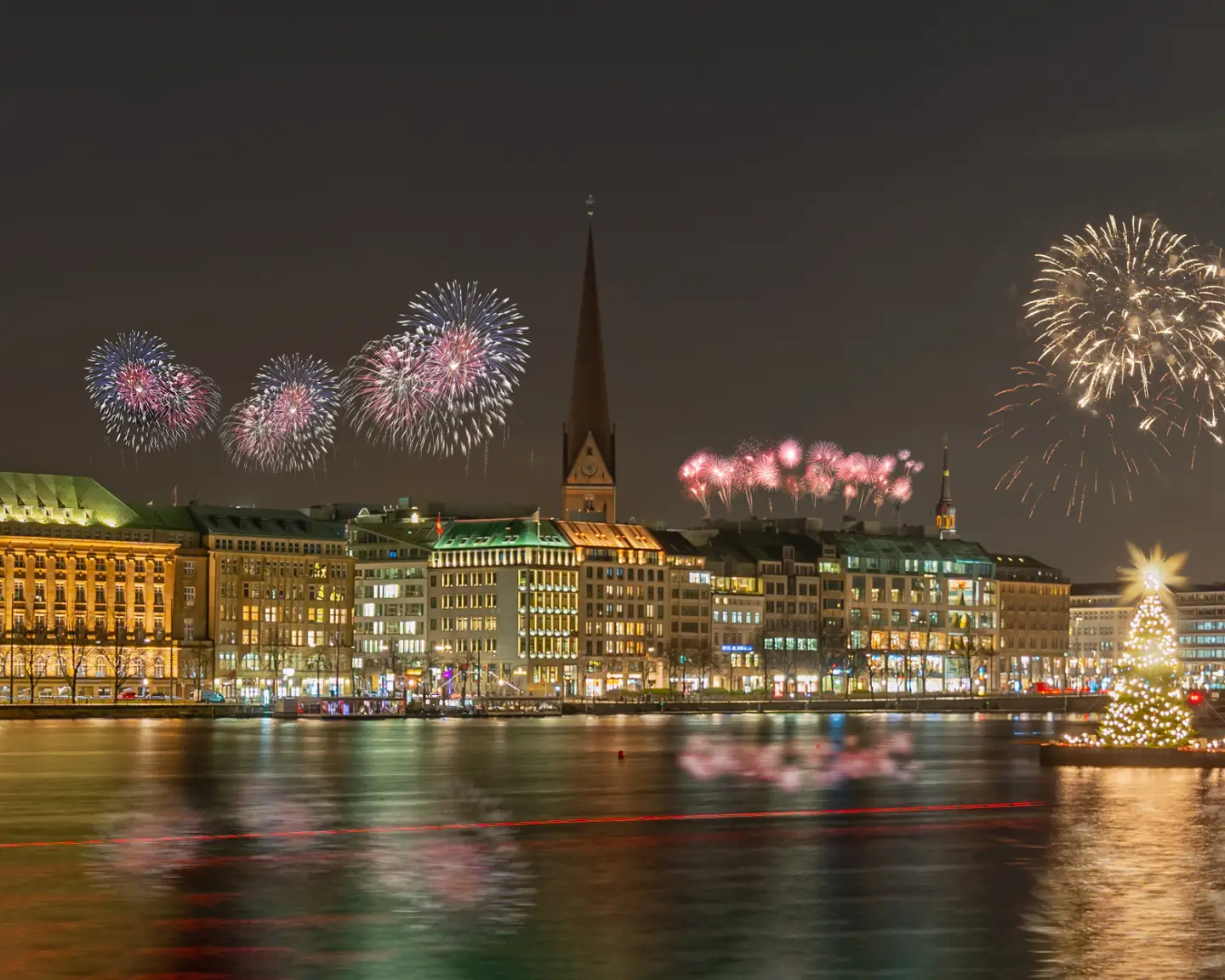 Silvesterfeuerwerk über der Hamburger Innenstadt und der Binnenalster bei Nacht.