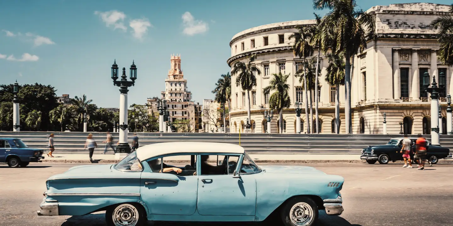 Old American car driving at a street of old Havana, Cuba