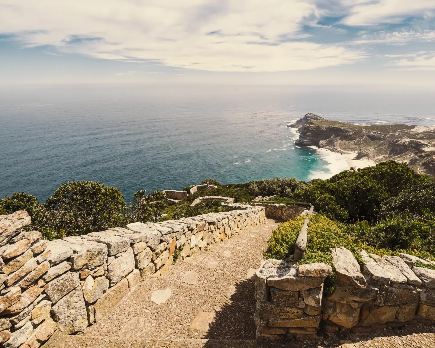 Blick von einem Küstenweg am Kap der Guten Hoffnung auf die felsige Atlantikküste und das Meer.