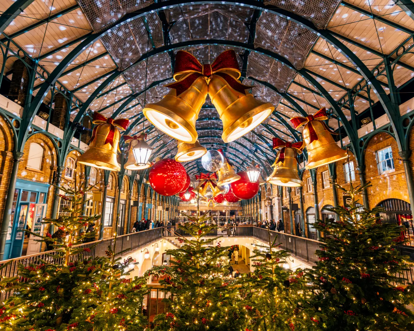 Festively decorated Covent Garden in London with illuminated Christmas trees, large golden bells and Christmas decorations.