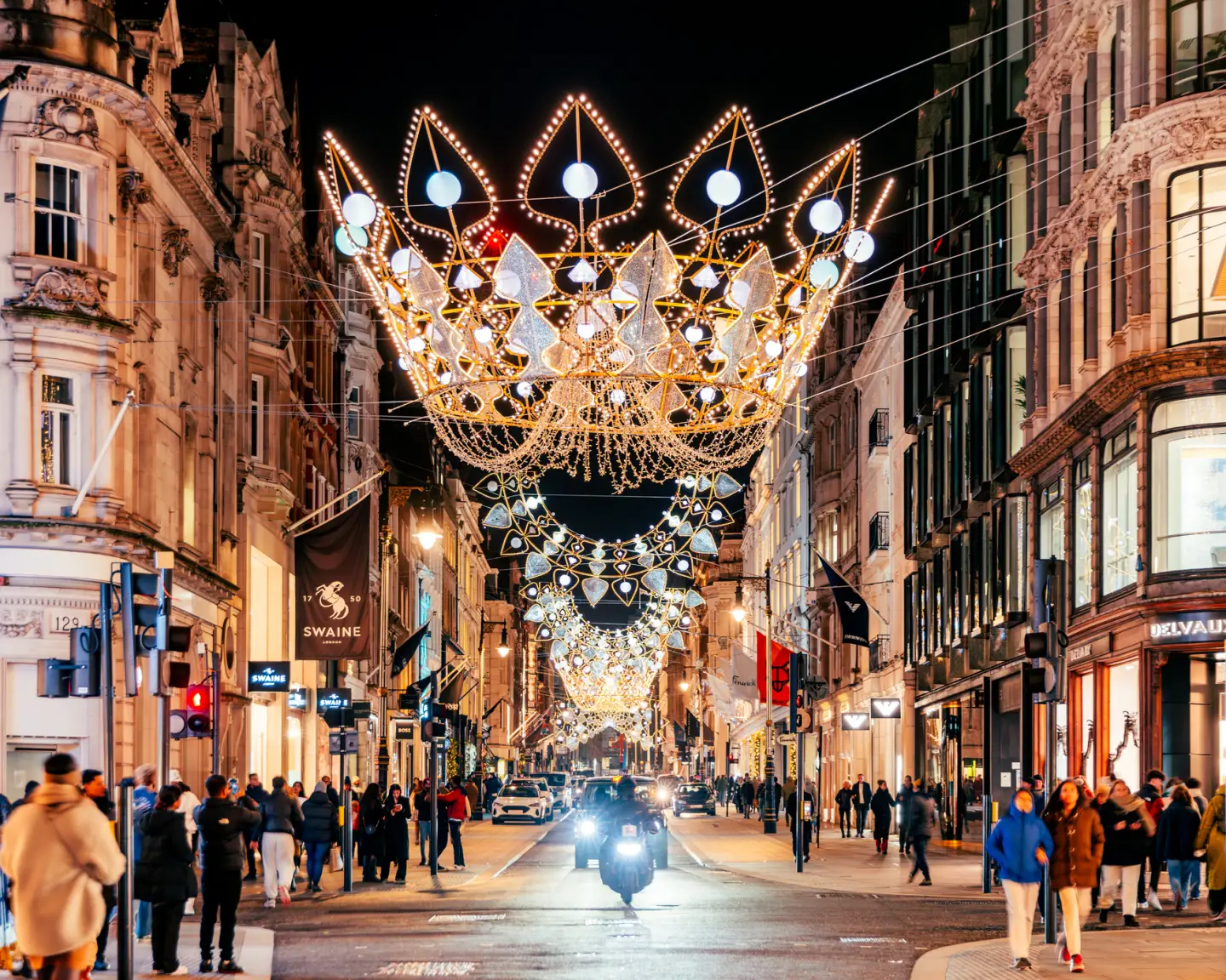 Weihnachtlich beleuchtete Bond Street in London mit aufwendigen Lichtinstallationen, Geschäften und Passanten am Abend.
